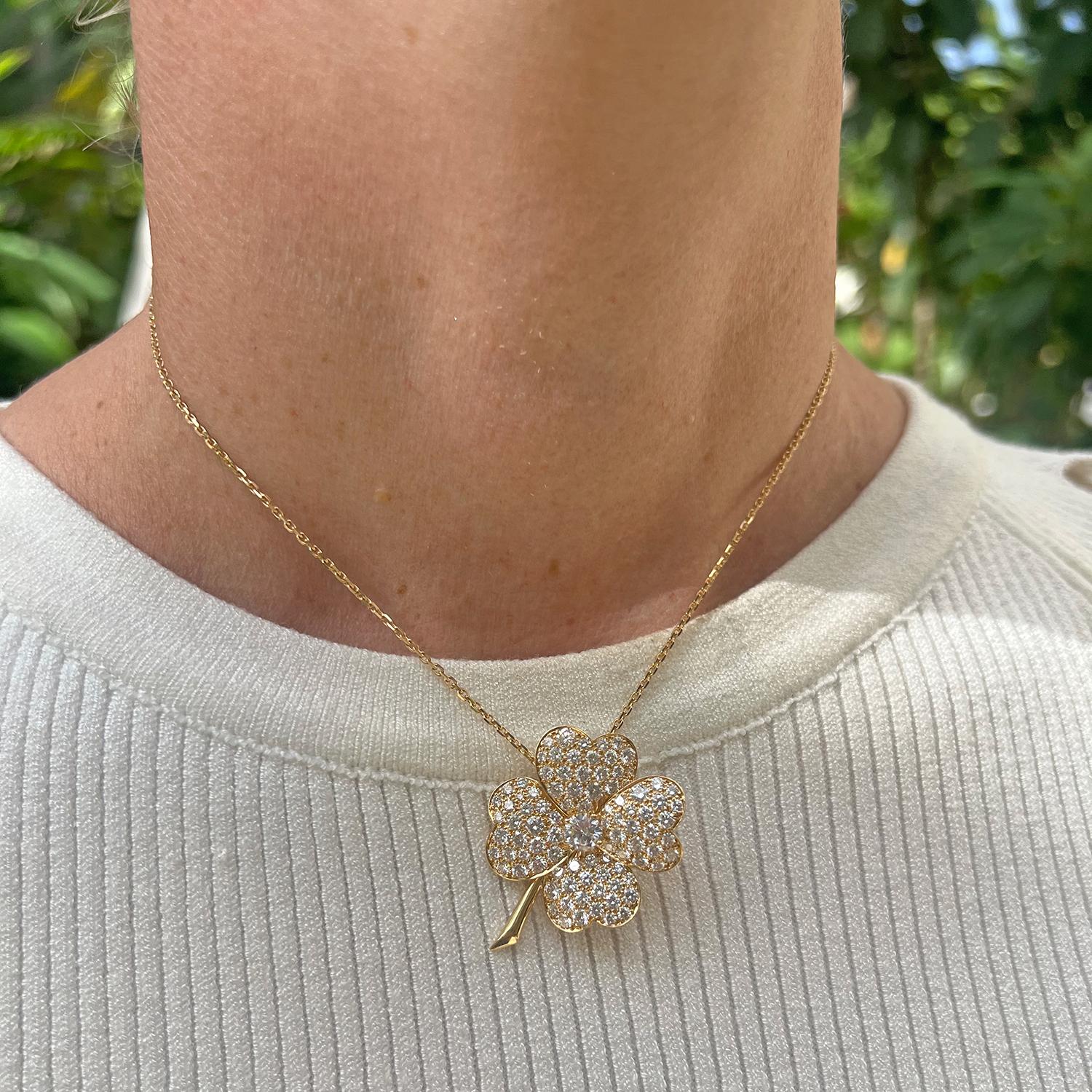 Van Cleef & Arpels Cosmos clip-style pendant/brooch in 18k yellow gold, featuring a larger central round brilliant-cut diamond surrounded by four petals pave-set with smaller round brilliant-cut diamonds with a polished floral stem. Clip suspended