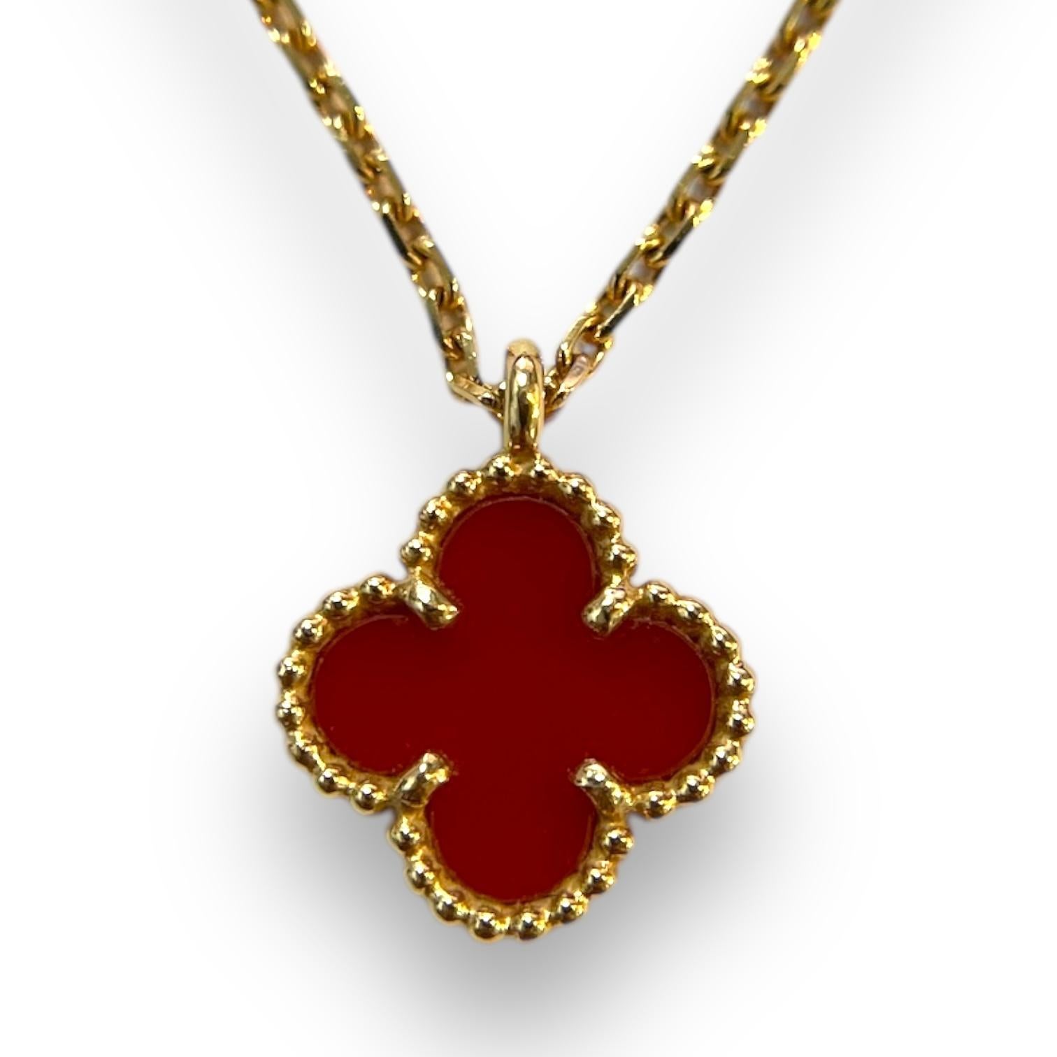 This authentic Van Cleef & Arpels Sweet Alhambra necklace radiates timeless sophistication. The clover-shaped pendant, a symbol of luck and joy, is crafted in luxurious 18K yellow gold and features a vibrant red carnelian center. Surrounded by