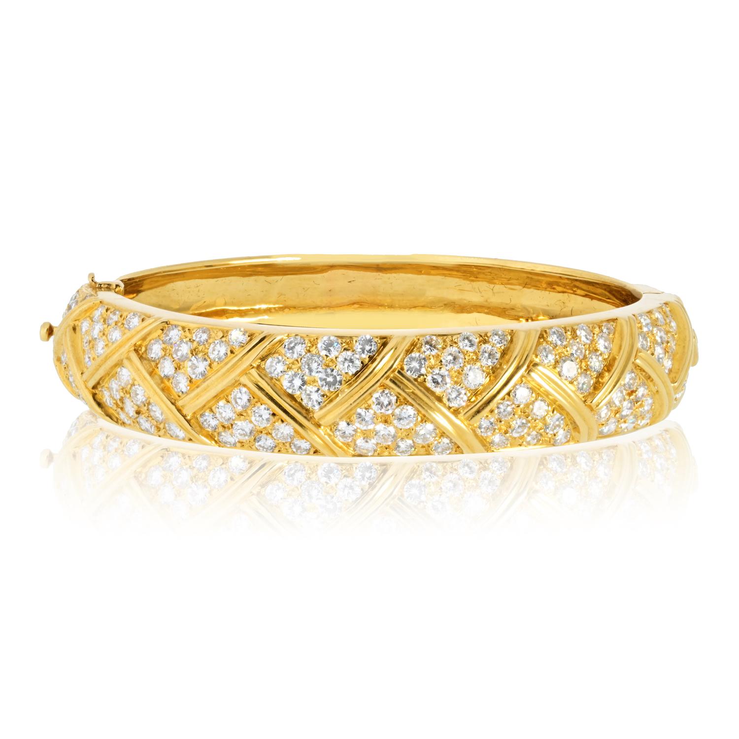 This vintage Van Cleef & Arpels hinged bangle bracelet is expertly crafted from 18K yellow gold, weighing 44 grams, and adorned with 4.80 carats of round-cut diamonds. 

Showcasing exceptional top-color, top-clarity stones, this elegant cuff
