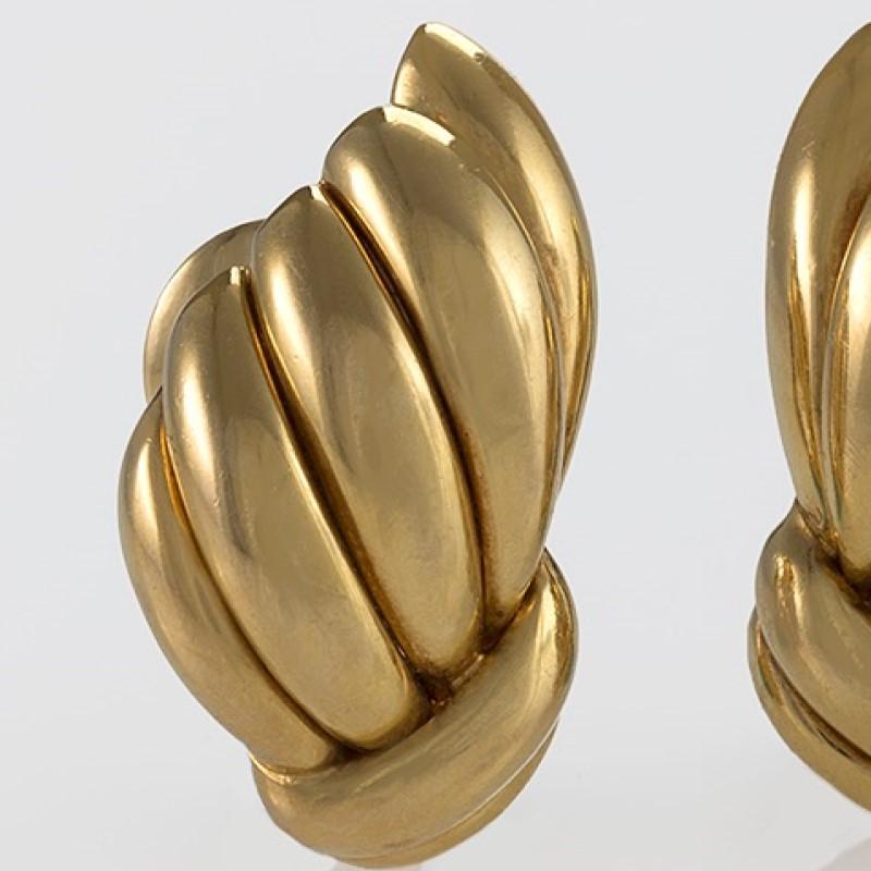 These gold earrings by Van Cleef & Arpels, dating from the 1960s, are shaped into a scalloped bombé wing motif. Voluminous, but not heavy, these beautifully-crafted bombé forms hug the ear with clipbacks, enlivening the face with gleaming