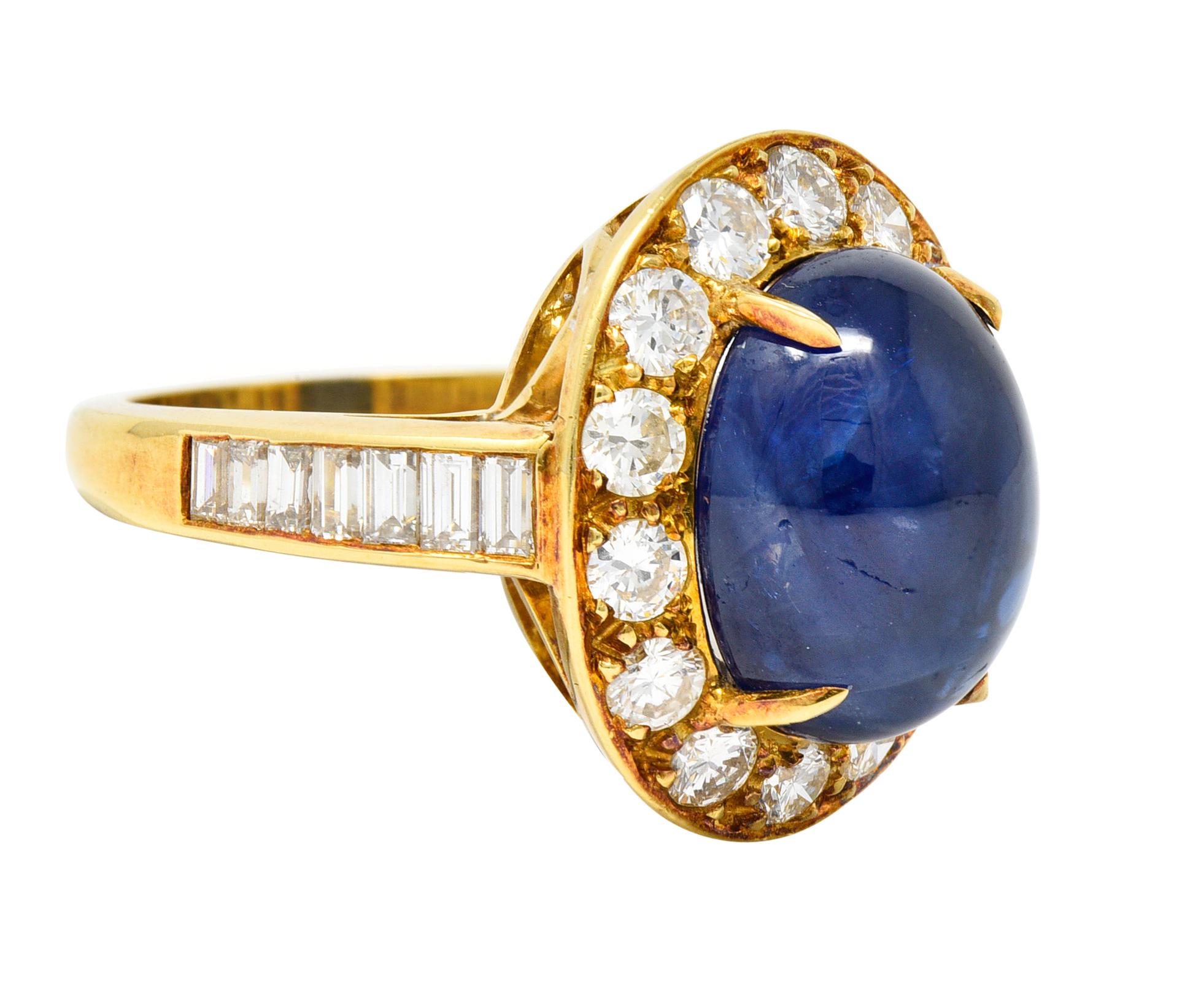 Centering an oval shaped sapphire cabochon weighing approximately 8.62 carats - transparent medium blue
Set with talon prongs with a halo surround of round brilliant cut diamonds
Flanked by cathedral shoulders with channel set baguette cut