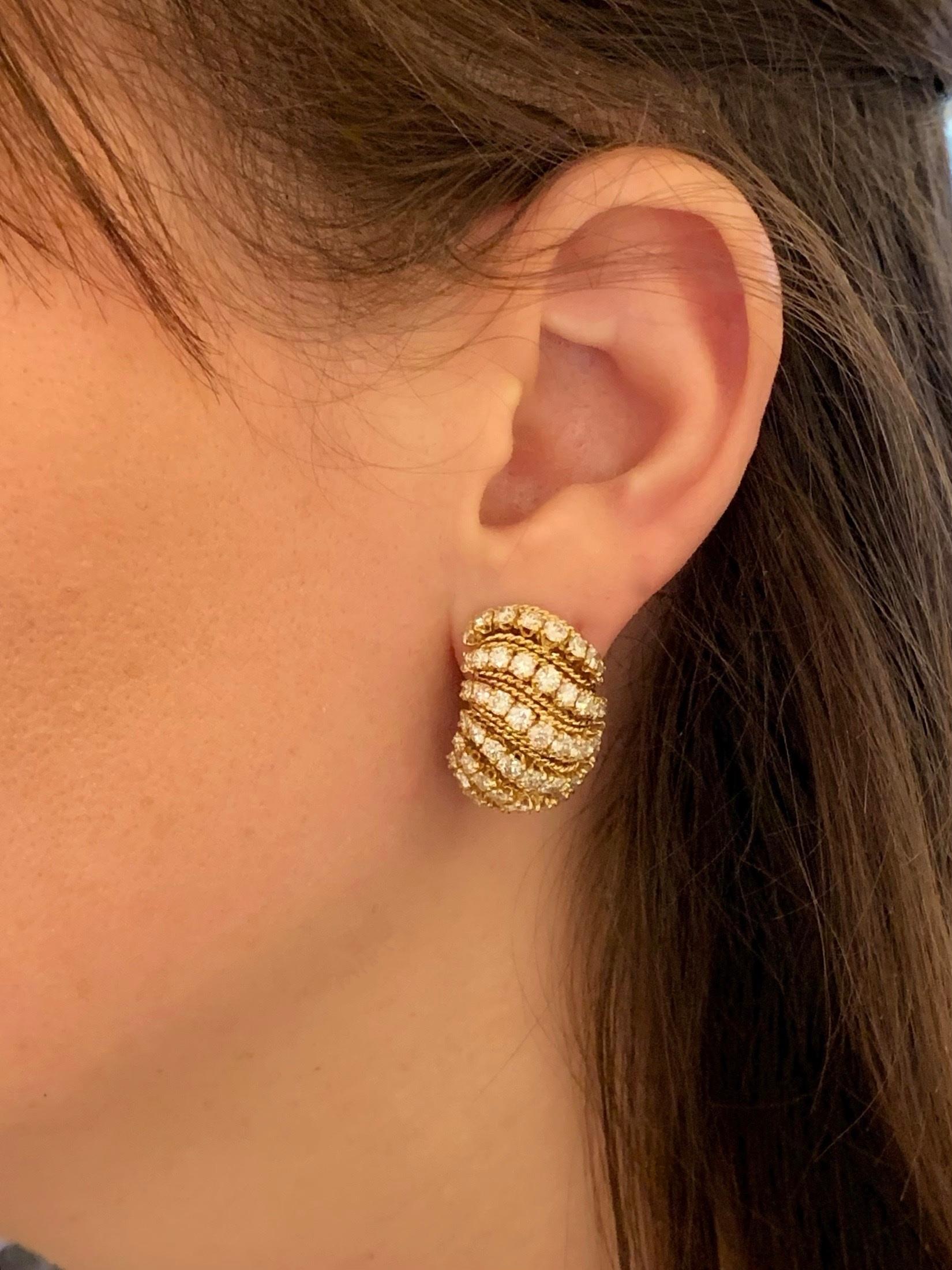 A pair of Mid-20th Century 18 karat gold earrings with diamonds by Van Cleef & Arpels. The earrings have 106 round-cut diamonds with an approximate total weight of 5.75 carats, F/G color, VS clarity. The earrings are designed in a bombé half-loop