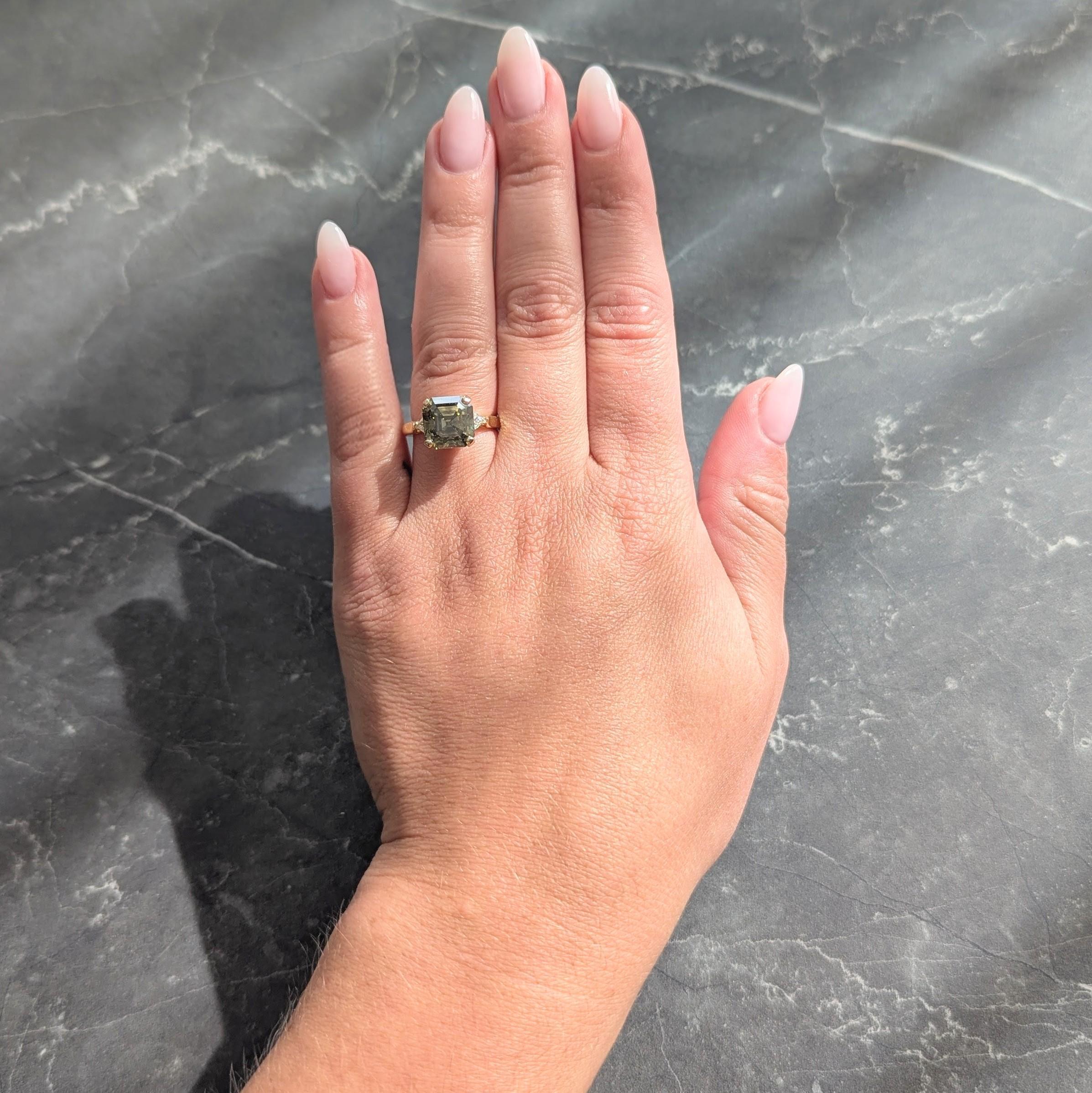 Centering an Asscher cut diamond weighing 5.01 carats
Fancy dark gray-yellowish green color with SI1 clarity - prong set
Basket is flanked by cathedral shoulders prong set with diamonds
Trilliant cut and weighing approximately 0.30 carat total
G