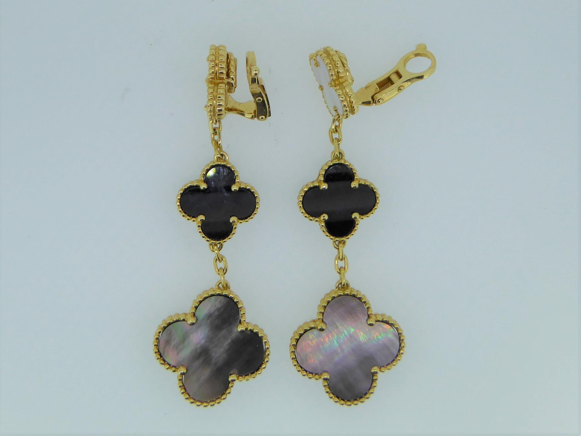 A pair of Van Cleef and Arpels Alhambra mother-of-pearl, onyx and 18ct yellow gold ear clips. Each ear clip with three graduating motif drops. Set in 18ct yellow gold. Each clip marked 