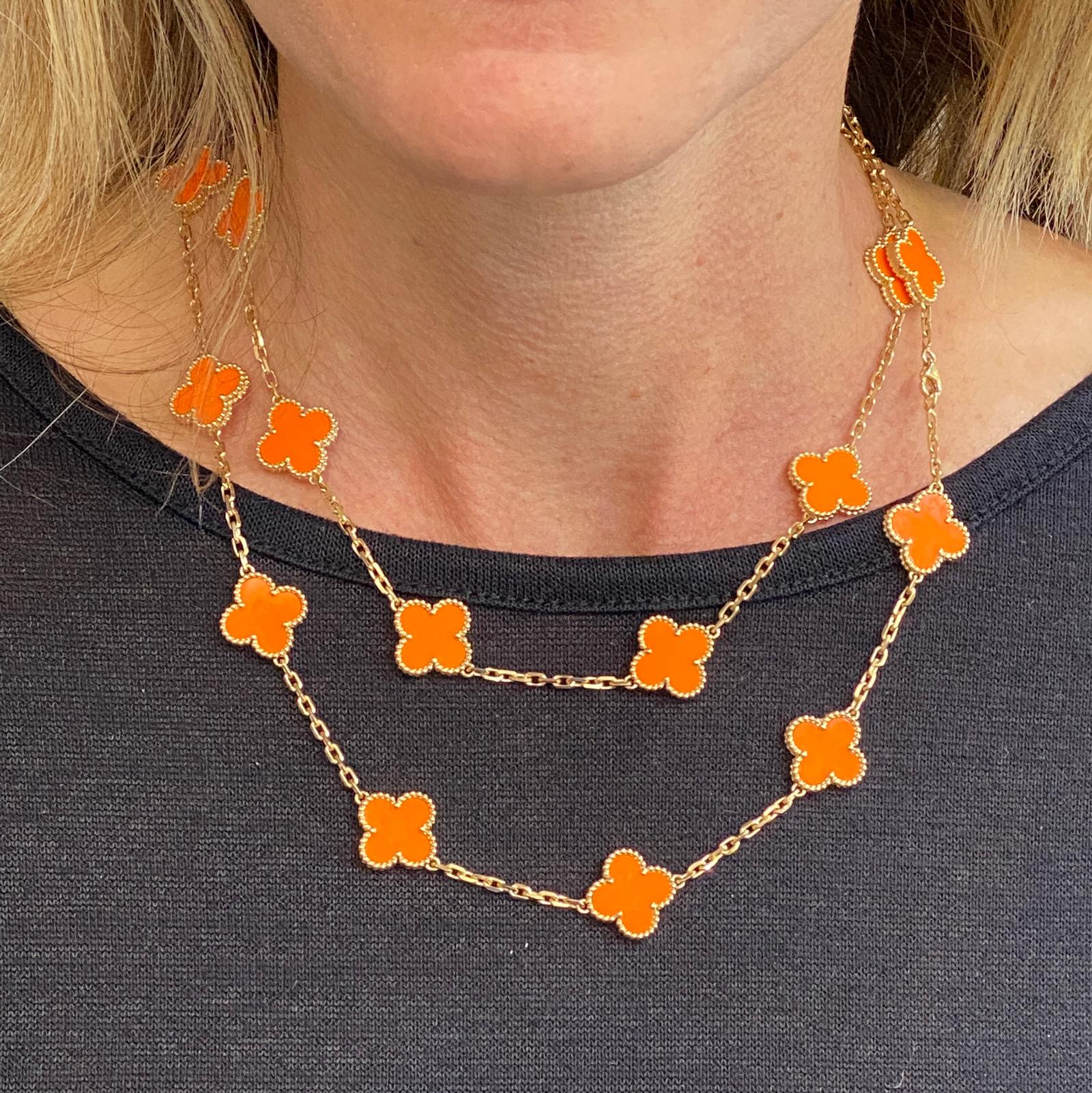 Rare Van Cleef & Arpels 20 Motif Alhambra orange coral necklace fashioned in 18 karat yellow gold. The necklace features 20 clover motif sections with orange coral inlay. The necklace measures 34 inches in length, is signed VCA, numbered, and