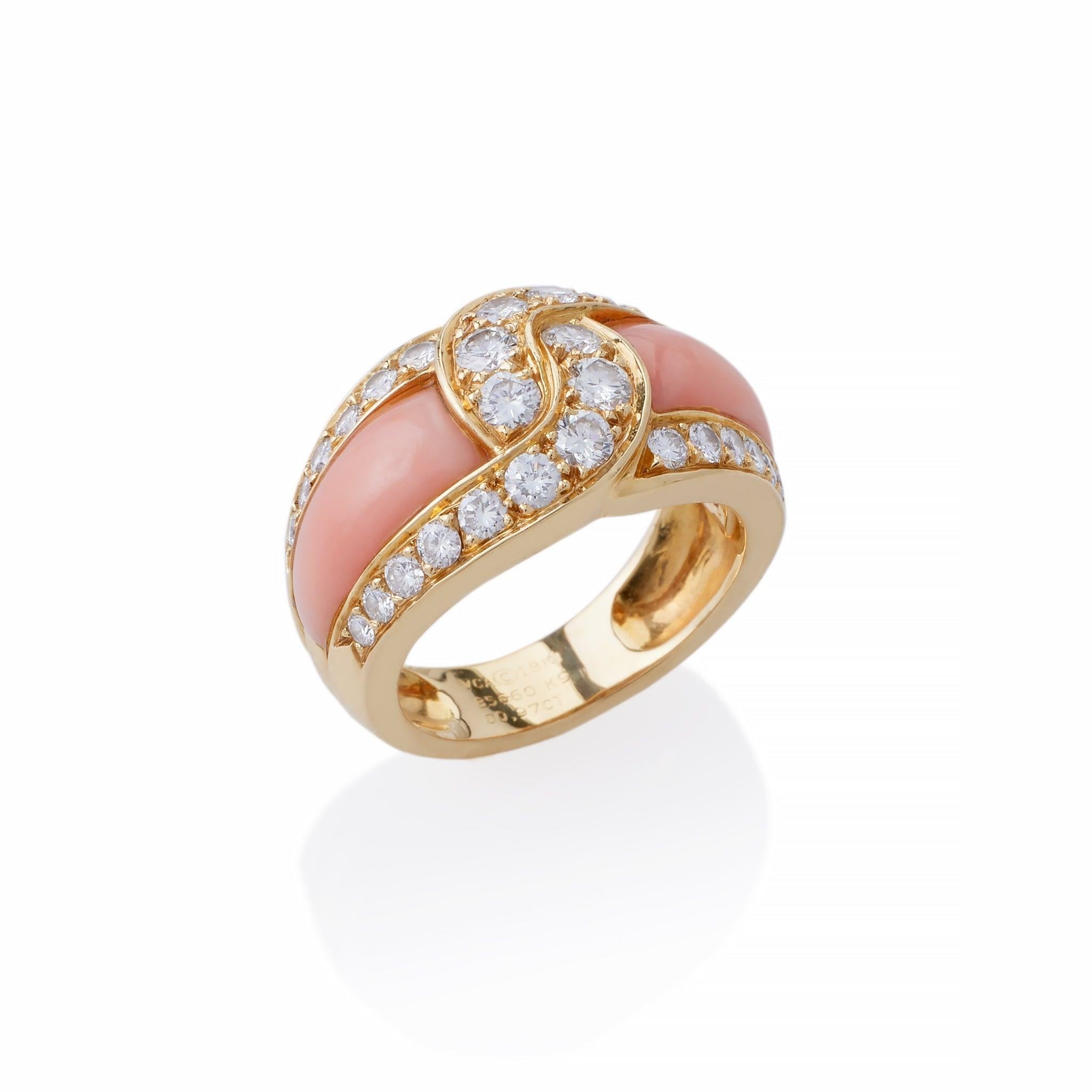 Dating from the 1980s, this 18K gold Van Cleef & Arpels ring is set with angel skin coral and diamonds. The ring features interlocking curved bands of round brilliant cut diamonds continuing along both edges, and framing shaped, pale orange coral