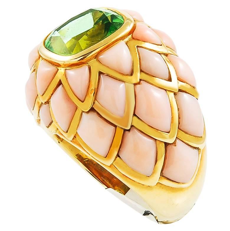 A quintessentially feminine ring by Van Cleef & Arpels circa 1980's, comprised of 18k yellow gold, accentuated with soft and serene angel skin coral, all surrounding a strikingly vibrant peridot in the center.
Signed Van Cleef & Arpels.
size 6