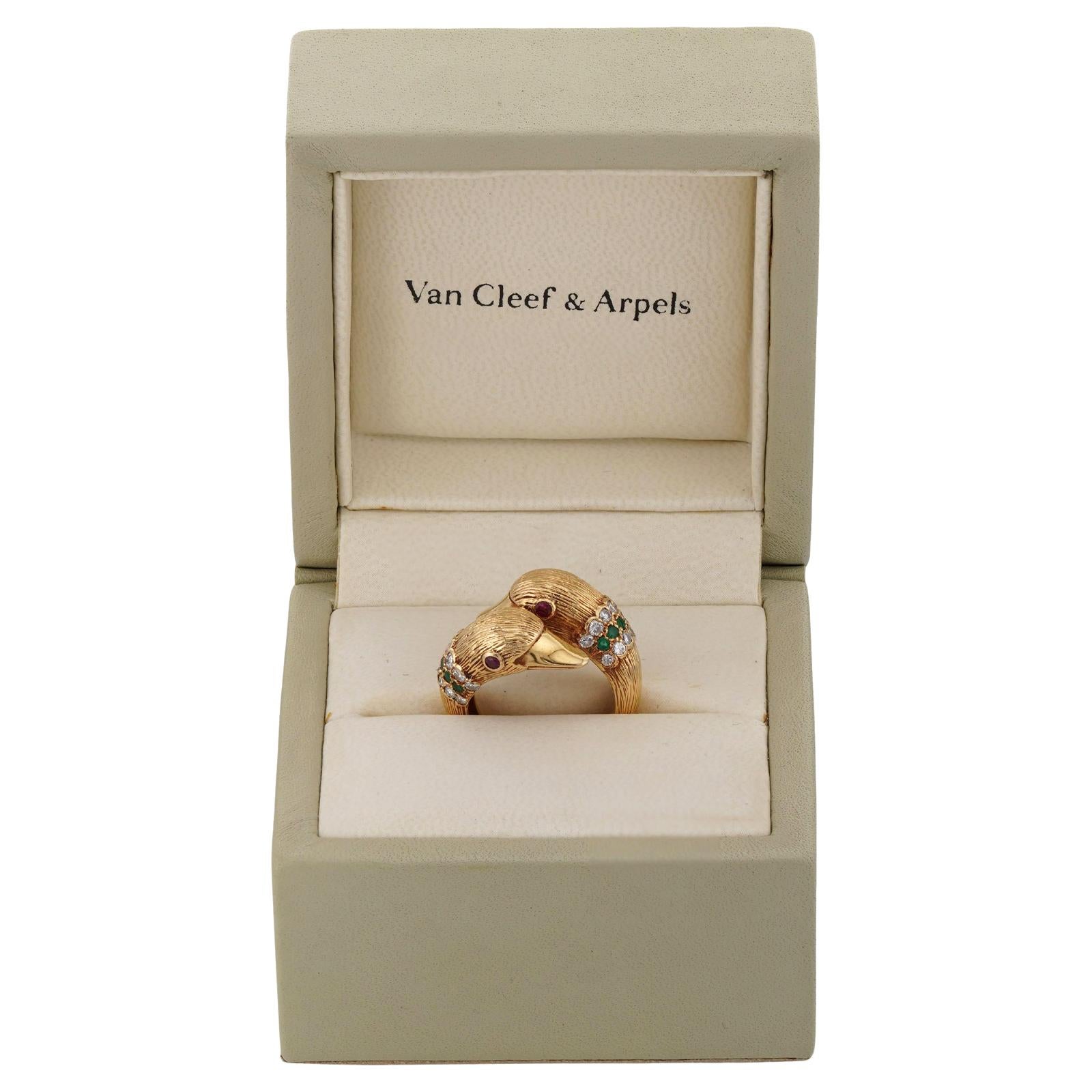 Dieser fantastische Bypass-Ring von Van Cleef & Arpels ist aus 18 Karat Gelbgold gefertigt und zeigt ein Paar geschnitzter, geriffelter rosa Korallen-Delphine, die mit roten Rubinen im Rundschliff, grünen Smaragden und runden Diamanten im