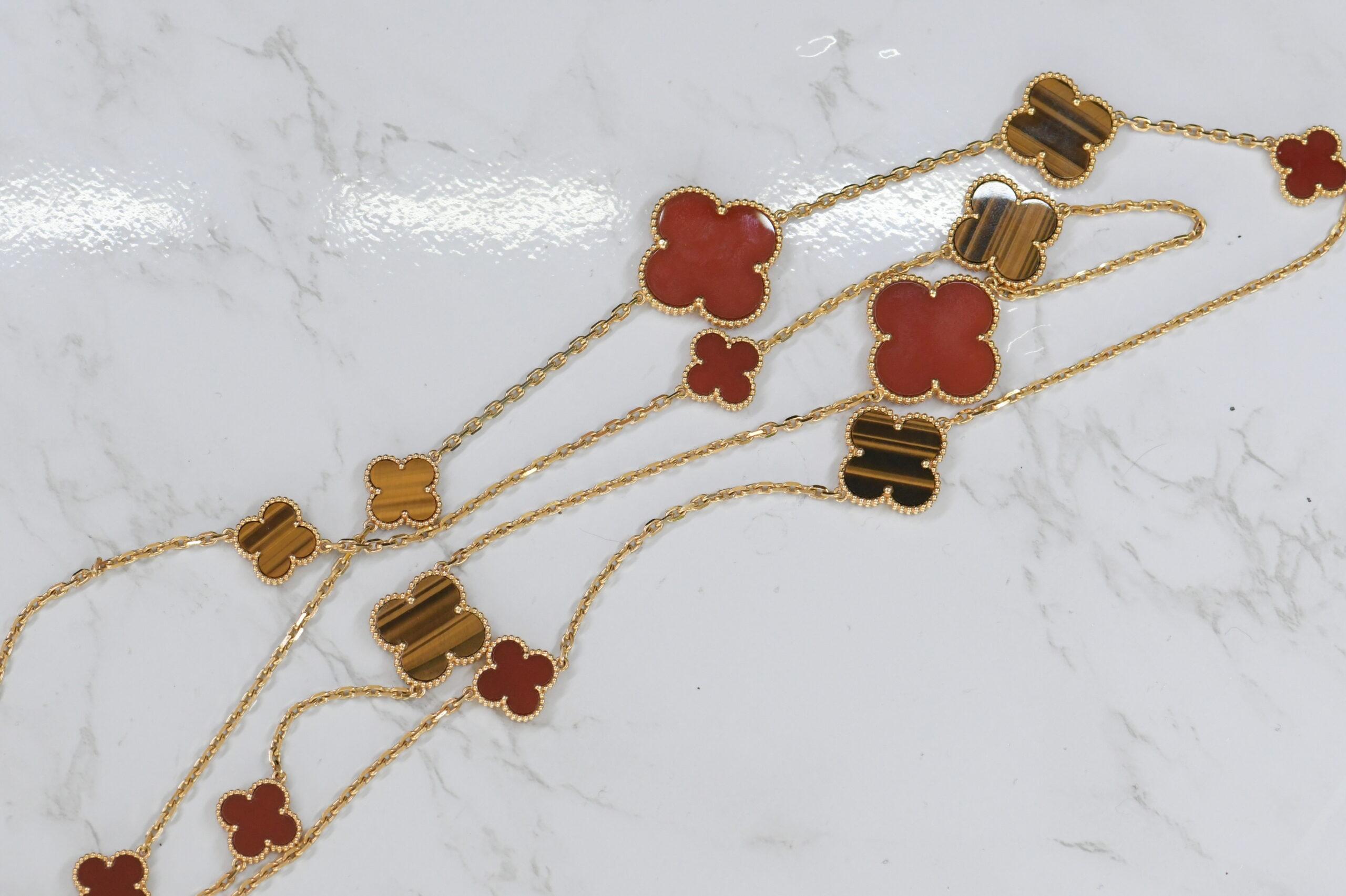 This Van Cleef & Arpels 18K gold necklace features 16 variously sized carnelian and tiger's eye quatrefoil motifs on a fine link chain. Necklace length 48 inches. French assay and workshop marks. Signed VCA, necklace numbered BL273863.
