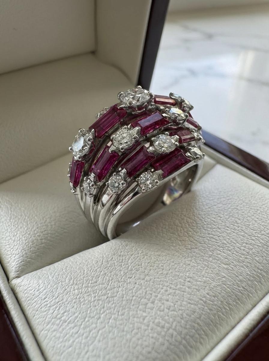 Cette exquise bague de cocktail dôme Van Cleef & Arpels est une remarquable création vintage réalisée dans un luxueux platine et entièrement authentifiée par le certificat officiel de la Maison. Le design présente un jeu harmonieux de rubis vibrants