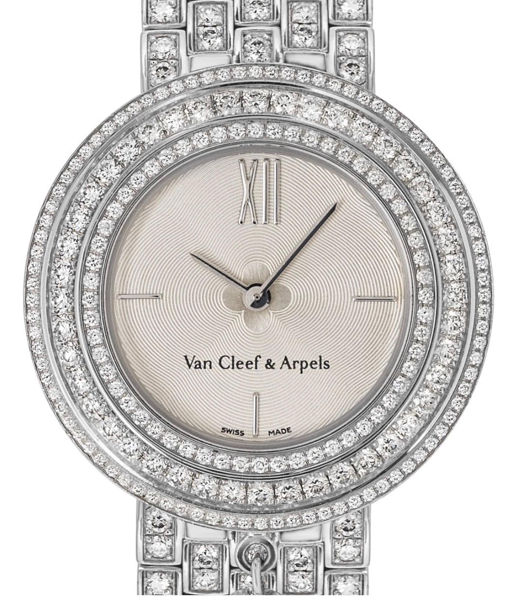 A striking ladies 32mm diamond set Charm wristwatch crafted in white gold by Van Cleef & Arpels. This timepiece features a silver guilloche dial with applied roman numeral XII and a white gold bezel set with round brilliant cut diamonds as well as a