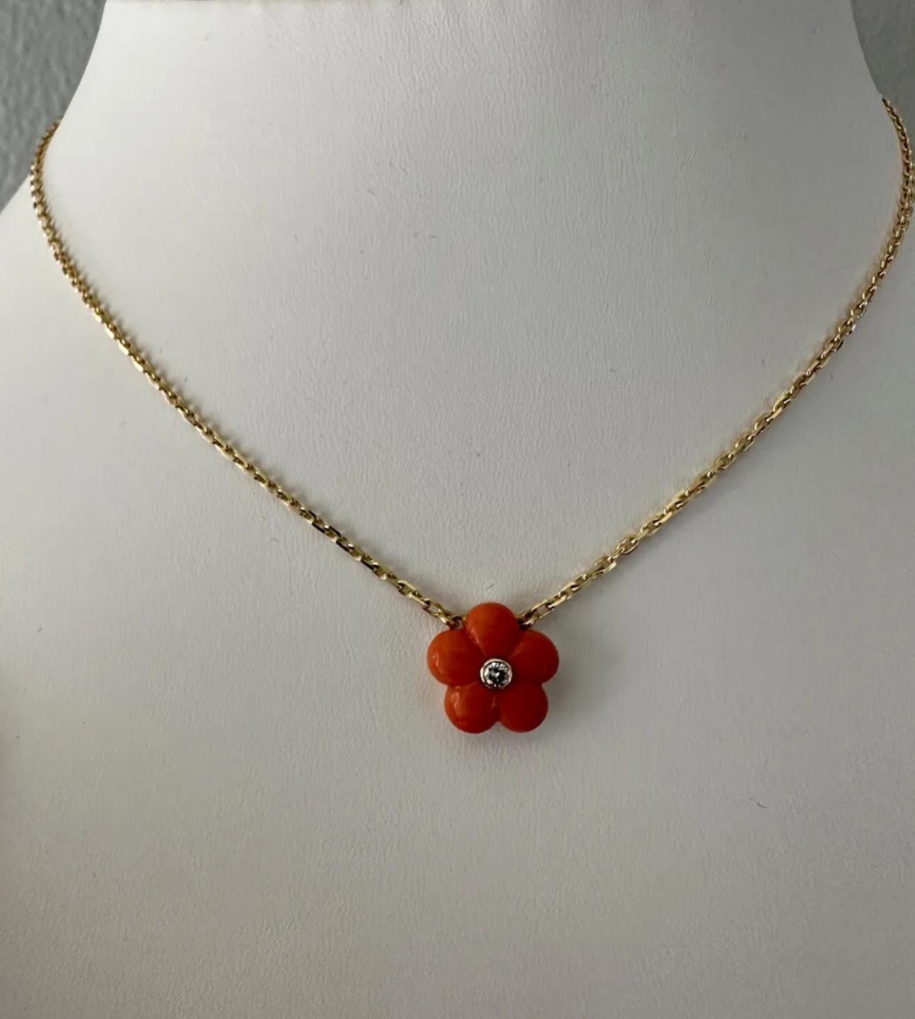 Van Cleef & Arpels pendant necklace features a stunning coral flower design with a diamond accent. The pendant is set in 18k yellow gold It is signed by the VCA and is a Flower style pendant. The main stone being coral and the secondary stone being