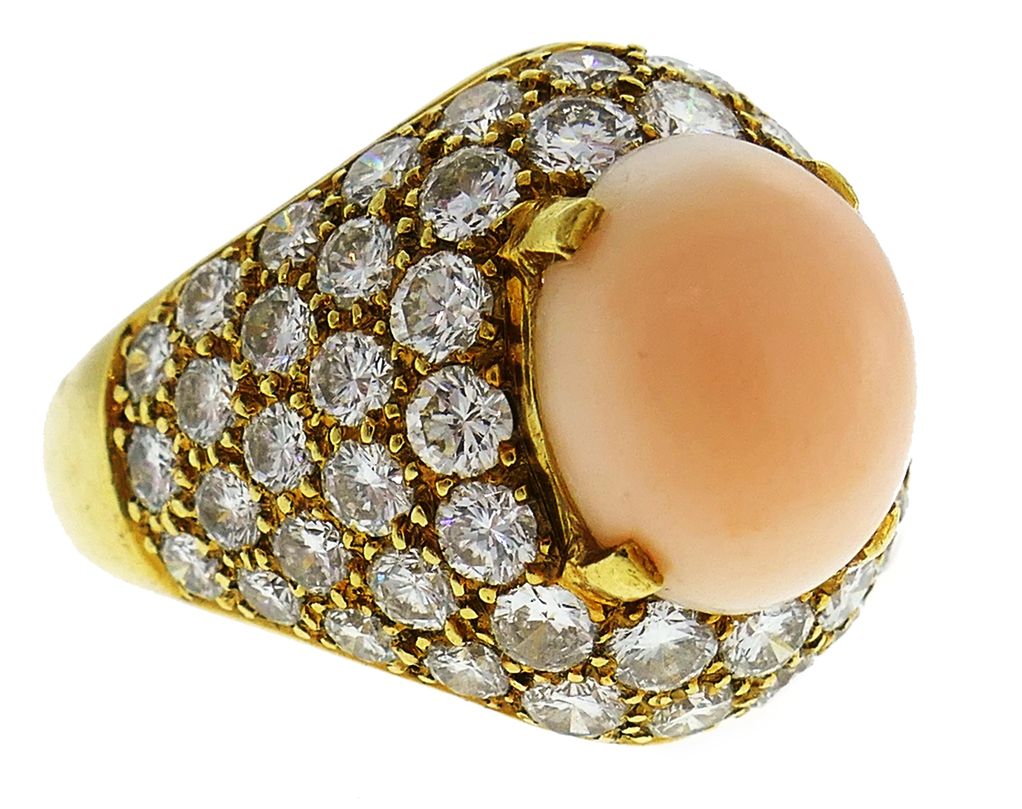 Bold yet elegant cocktail ring created by Van Cleef & Arpels in the 1970s. Features an oval cabochon angel skin coral set in yellow gold and accented with round brilliant cut diamonds. Timeless, classy and wearable, the ring is a great addition to