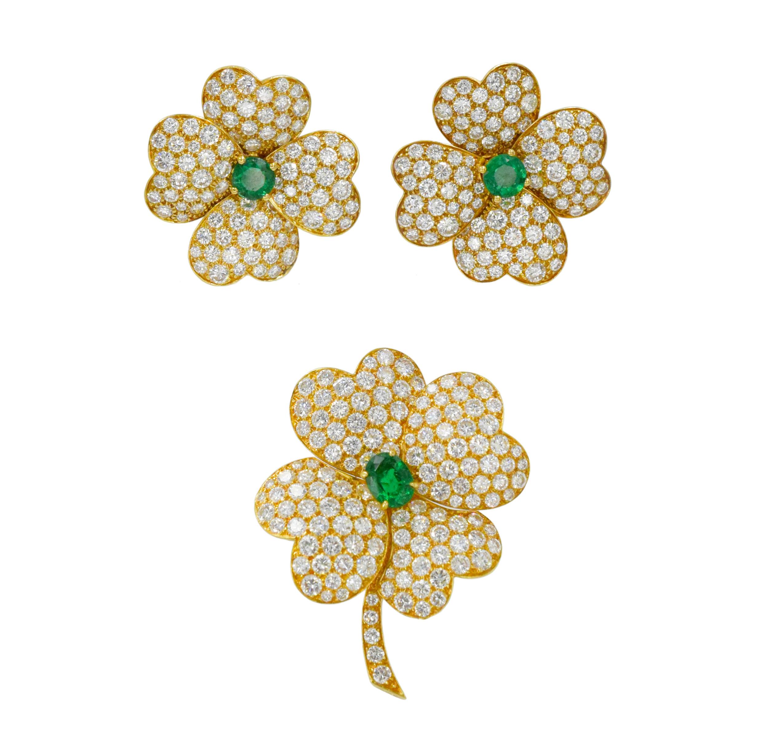 Van Cleef & Arpels 'Cosmos' diamond and emerald earrings
and brooch suite in 18k yellow gold. The brooch features a flower motif with 4 petals and a stem encrusted with round brilliant cut diamonds and oval cut emerald center. There is total of 136