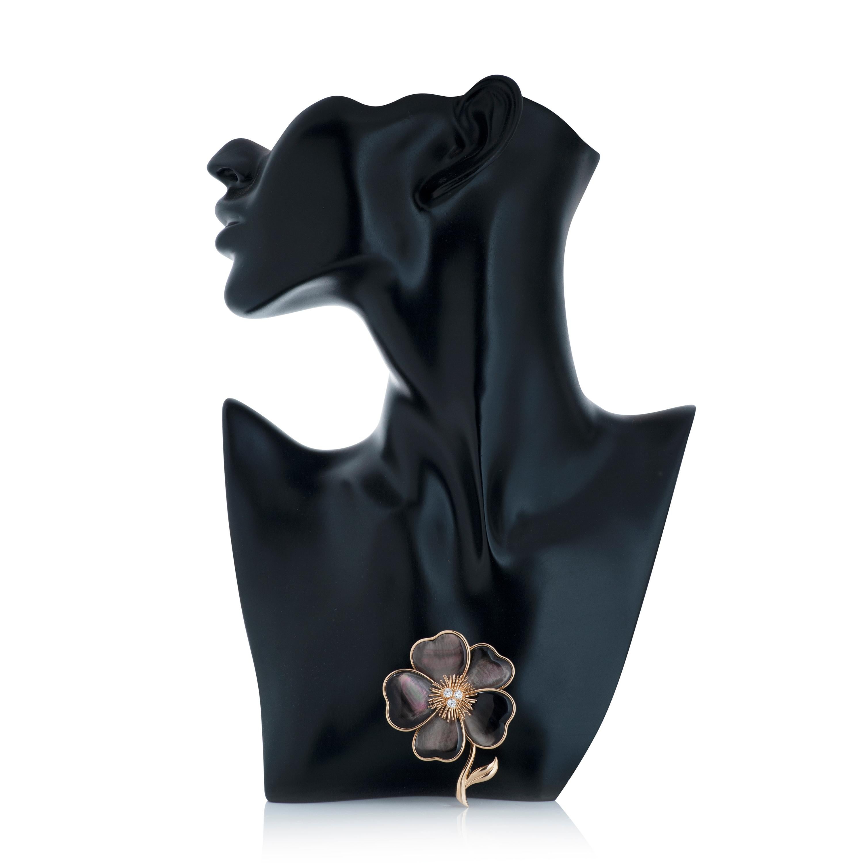 Van Cleef & Arpels diamond and mother of pearl Clematis flower brooch in 18k yellow gold.

This VCA brooch features 5 gray mother of pearl petals with 3 round brilliant cut diamonds set in the center.  The total diamond weight of the brooch is