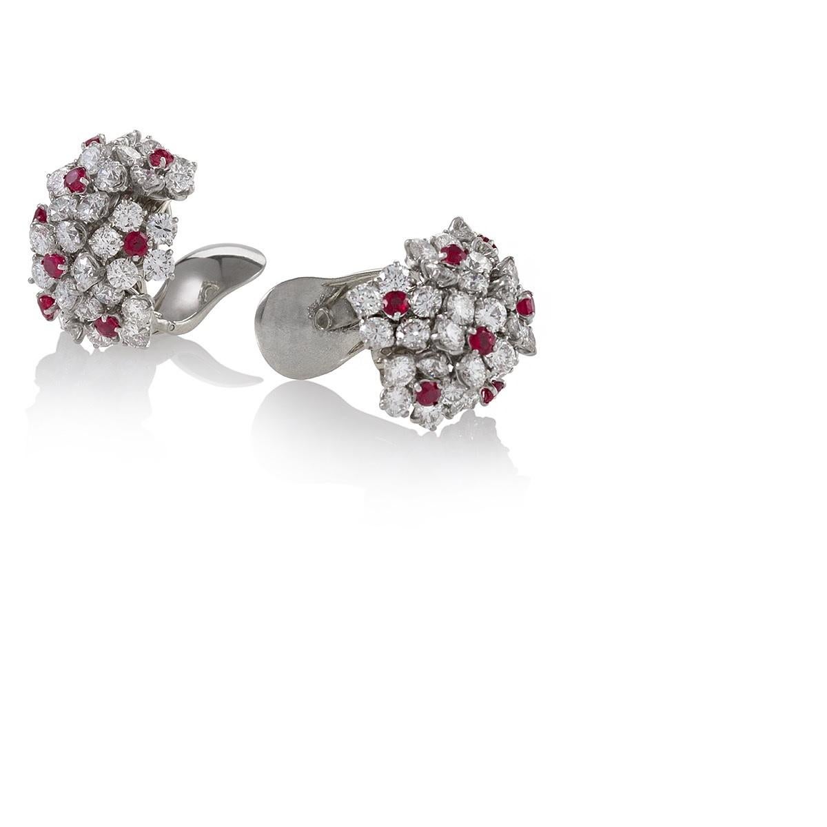 A pair of ruby and diamond cluster earrings by Van Cleef and Arpels. Set in platinum, the earrings feature clusters of round brilliant-cut diamonds with an approximate total weight of 12 carats, interspersed with 16 beautifully matched round rubies.