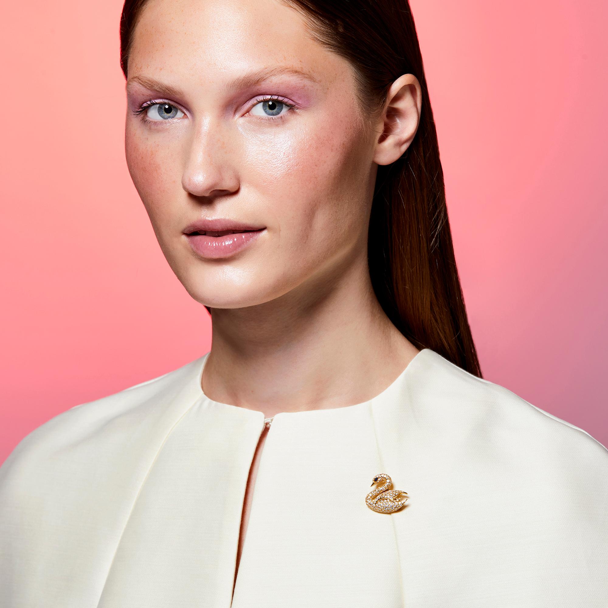 Designed as a perfect swan, this brooch is set with round diamonds and a marquise-cut sapphire eye, mounted in 18k yellow gold. The contrast of the 18k yellow gold against the full-cut diamonds creates a bombe effect that makes the swan come