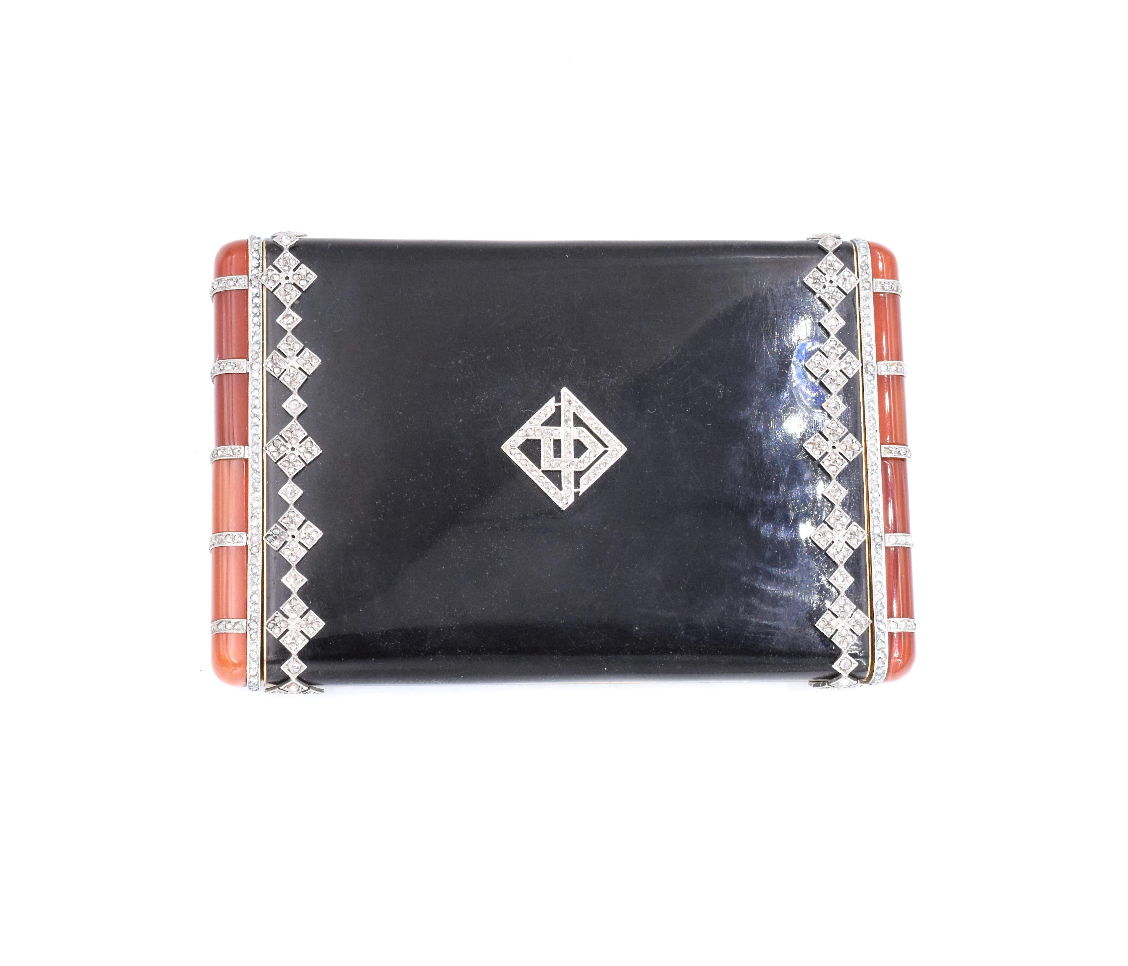 VCA Diamond, Black Enamel, and Orange Gemstone Compact. This compact has diamonds in filigree around the exterior of the box along with orange stones on the ends
. Signed Van Cleef & Arpels, Numbered: xxxx .
 Measurements: 3.5 inches by 2.25 