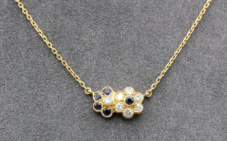 Fine sapphire diamond and 18K yellow gold pendant necklace by Van Cleef & Arpels. Designed as two interlocked flowers, it features rich blue sapphires of .50 carats and high grade diamonds of .48 carats.  Well made and easy to wear, makes a