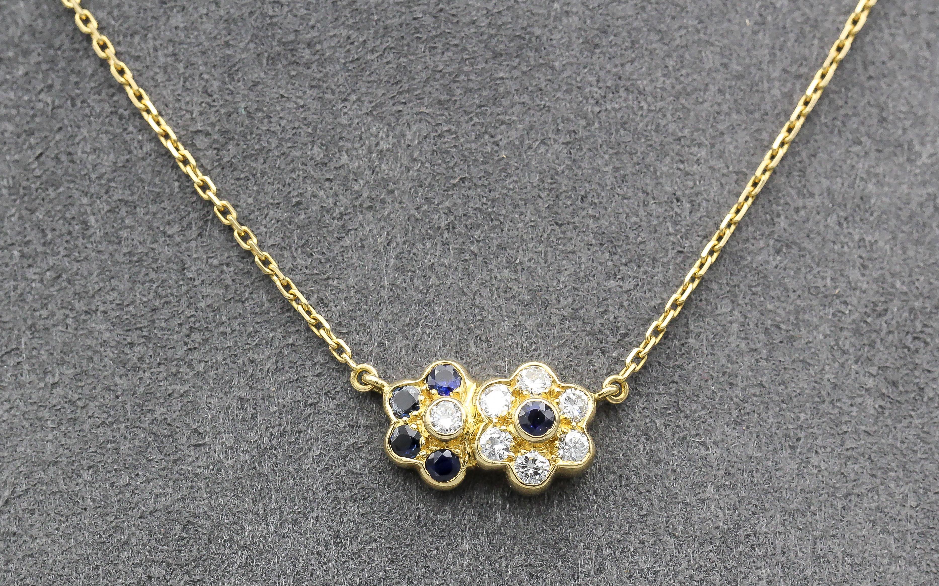 Introducing the Van Cleef & Arpels Sapphires and Diamond 18K Yellow Gold Pendant Necklace, a masterpiece of luxury and craftsmanship that captures the essence of timeless elegance. This exquisite necklace is designed as two interlocked flowers, with