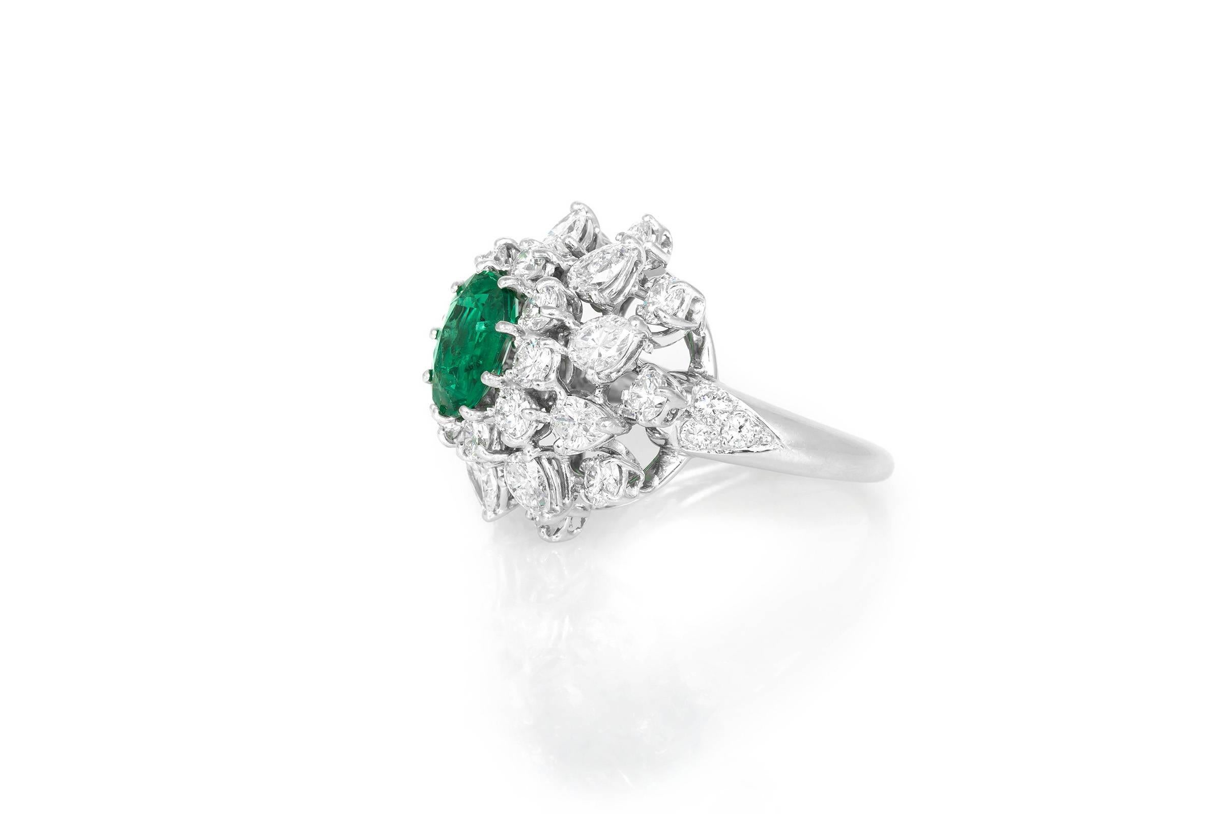 Signed by Van Cleef and Arpels finely crafted in platinum ring featuring a beautiful oval shaped emerald weighing 1.80 carat with a cluster of diamonds weighing 4.00 carat.