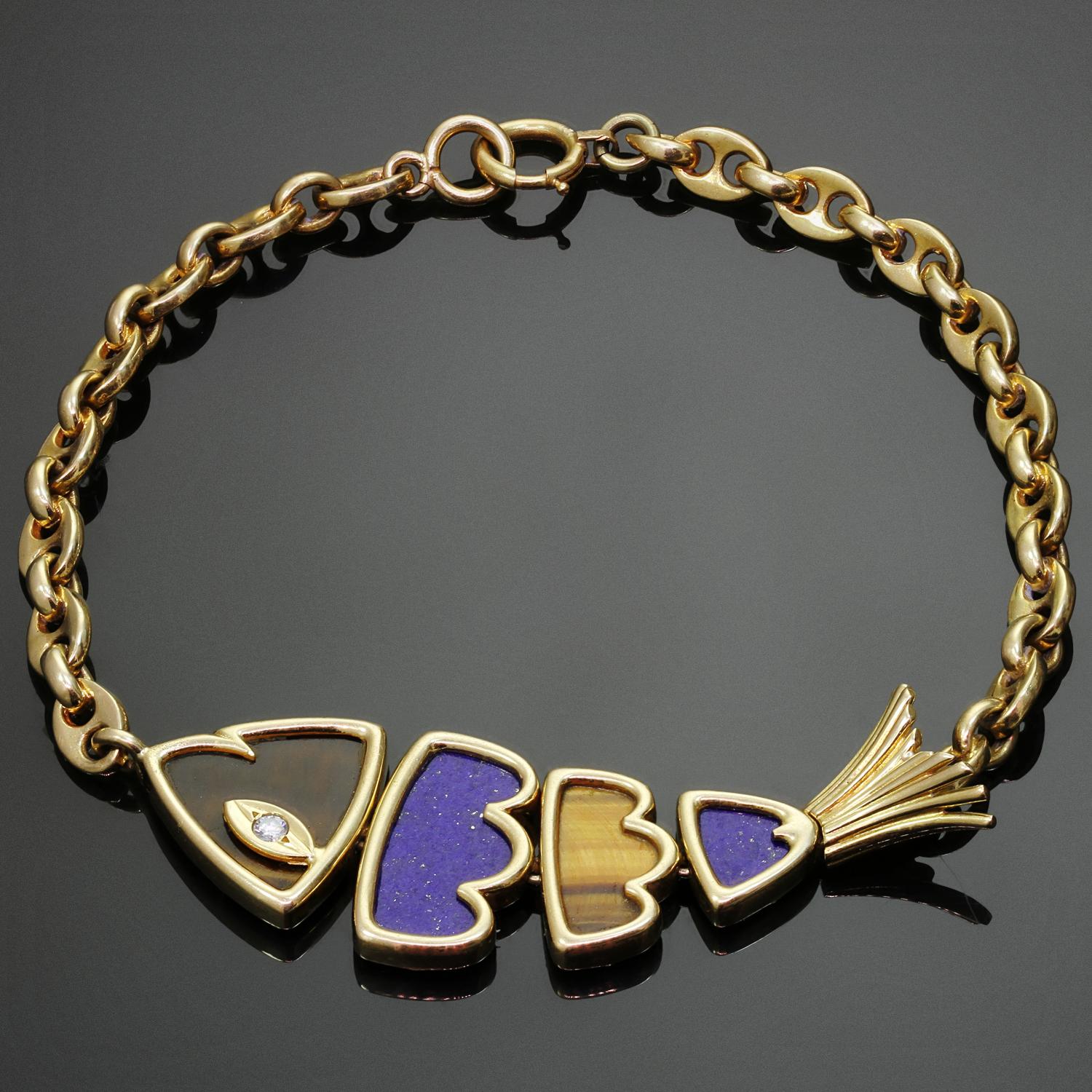 Ce fabuleux bracelet vintage Van Cleef & Arpels en or jaune 18 carats présente une breloque en forme de poisson incrustée de lapis-lazuli et d'œil de tigre et sertie d'un diamant rond taille brillant d'un poids estimé à 0,03 carat. Fabriqué en