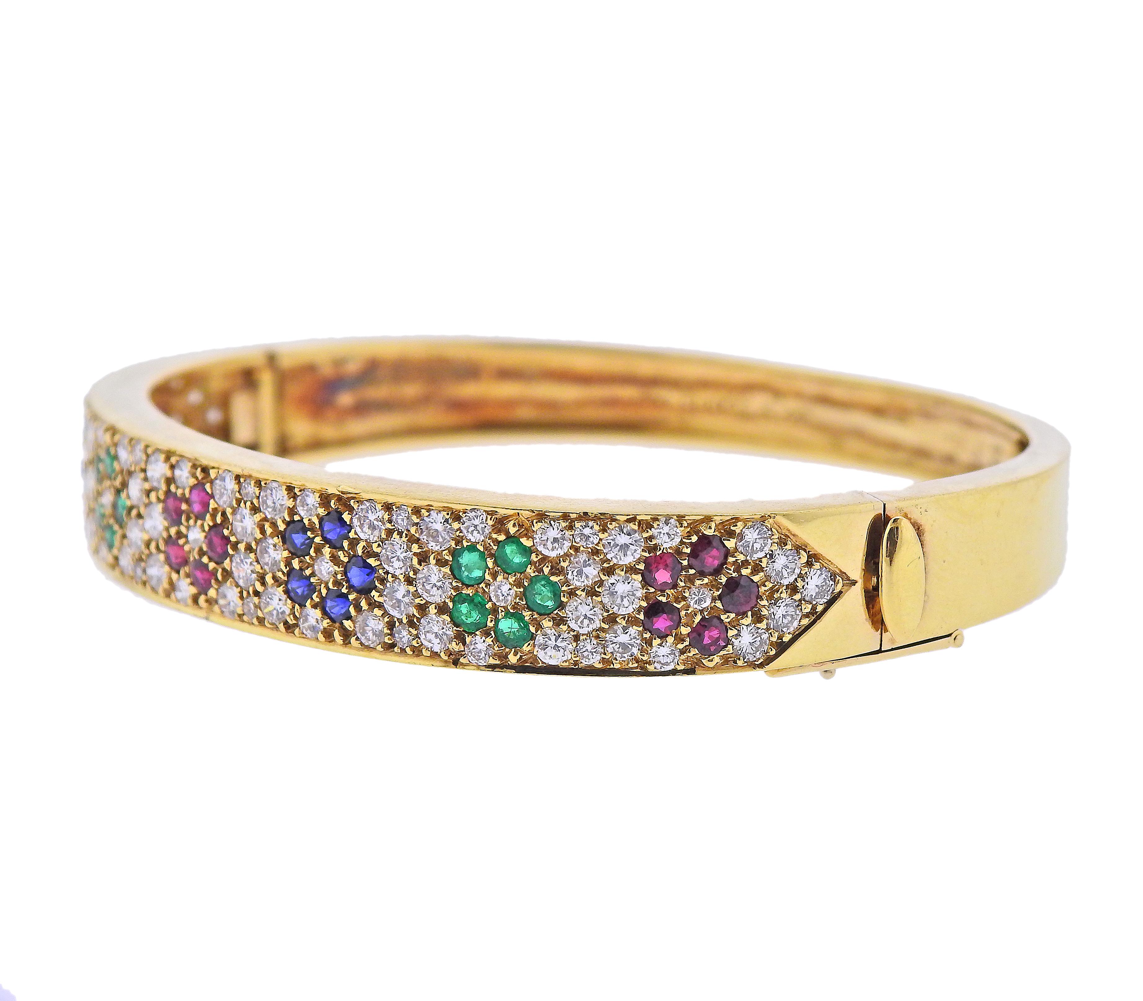 18k yellow gold bangle bracelet by Van Cleef & Arpels, featuring flowers, set in rubies, emeralds, sapphires and surrounded with approx. 2.40ctw in diamonds. Bracelet will fit approx. 7
