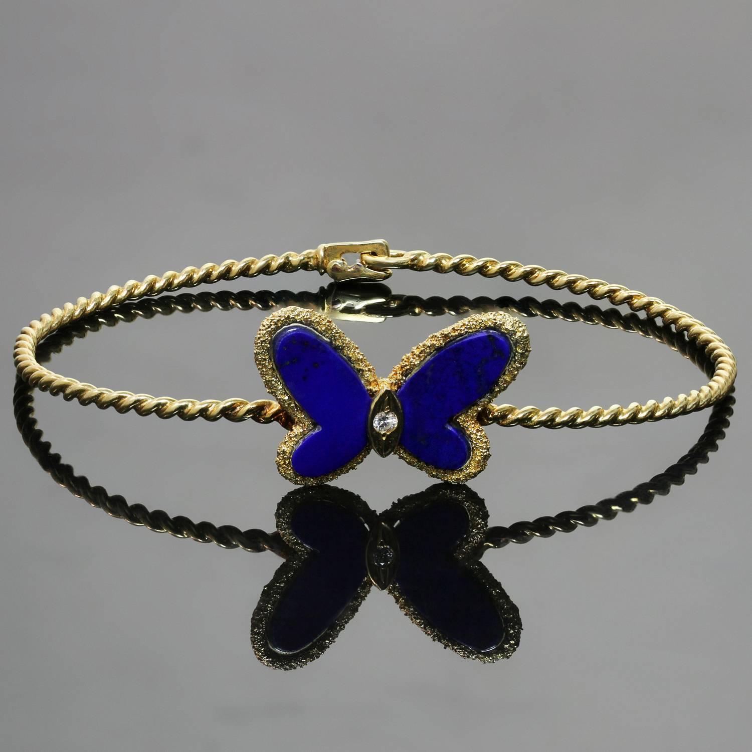 This stunning vintage Van Cleef & Arpels bracelet from the iconic Flying Beauties collection is crafted in textured 18k yellow gold and accented with a butterfly set with blue lapis lazuli wings and a solitaire brilliant-cut diamond of an estimated