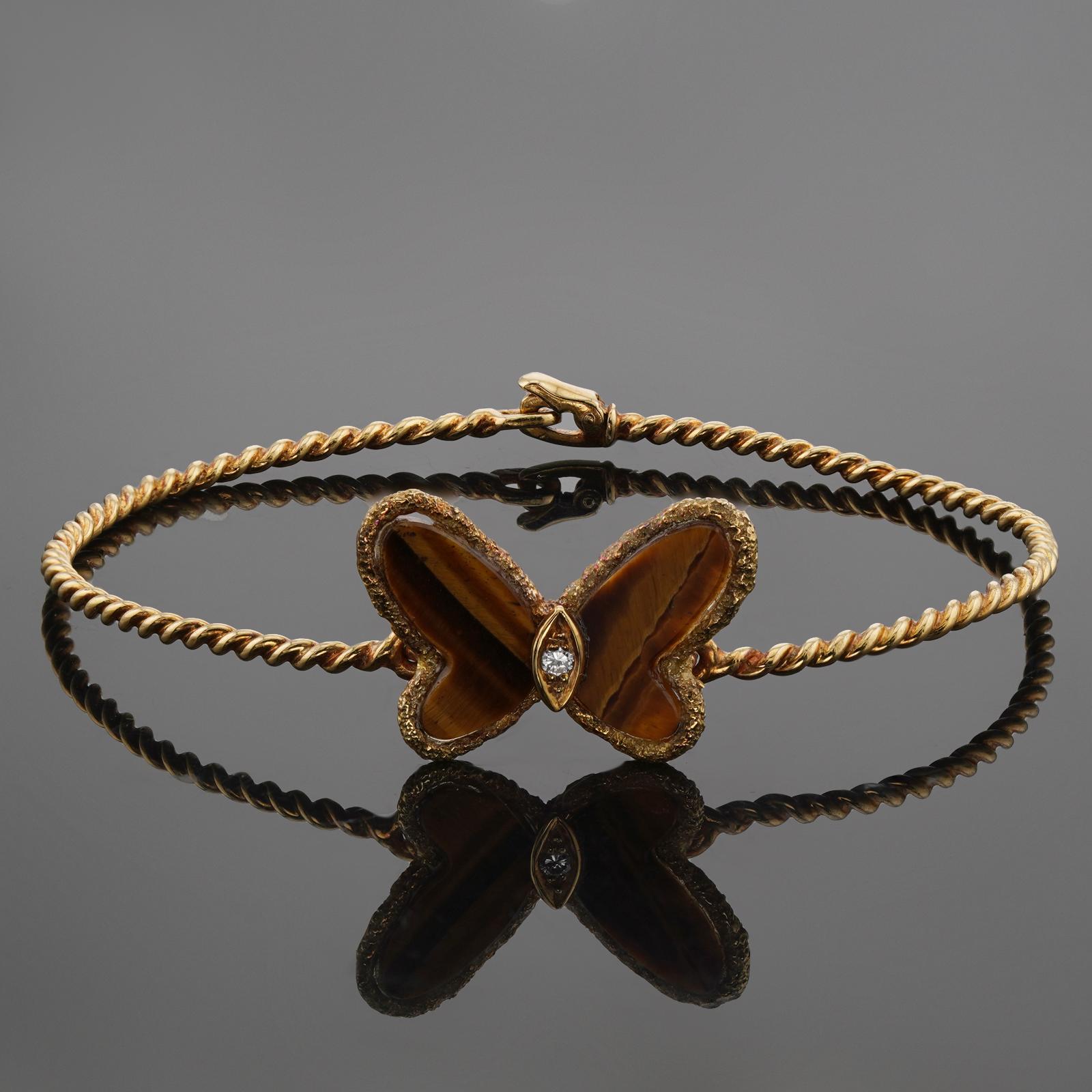 This stunning vintage Van Cleef & Arpels bracelet from the iconic Flying Beauties collection is crafted in textured 18k yellow gold and accented with a butterfly set with Tiger eye wings and a solitaire brilliant-cut diamond of an estimated 0.03