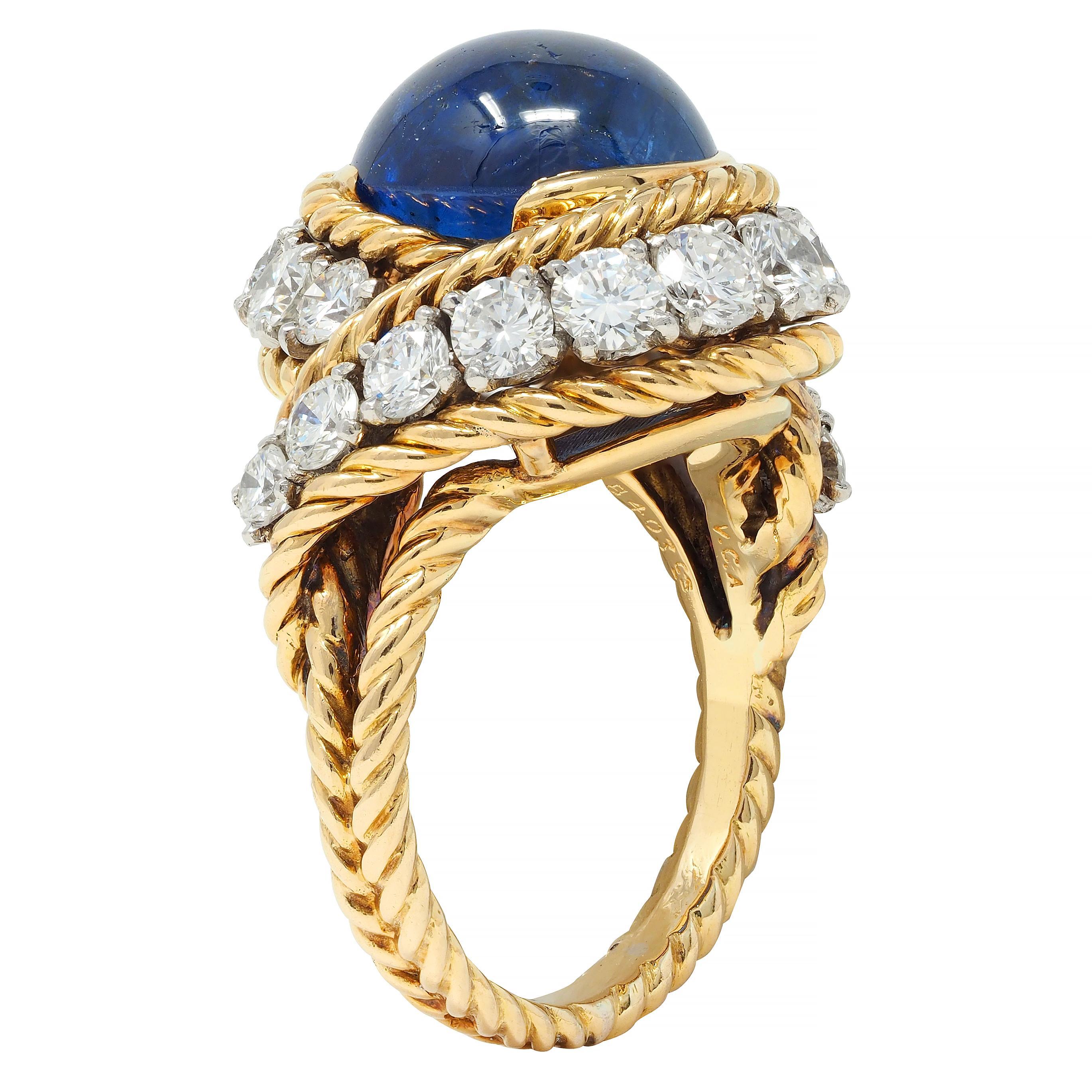 Centering an oval-shaped sapphire cabochon weighing approximately 8.74 carats 
Transparent dark blue in color and set in semi bezel with twisted rope surround 
Curling around sapphire with rows of graduated round brilliant cut diamonds 
Weighing