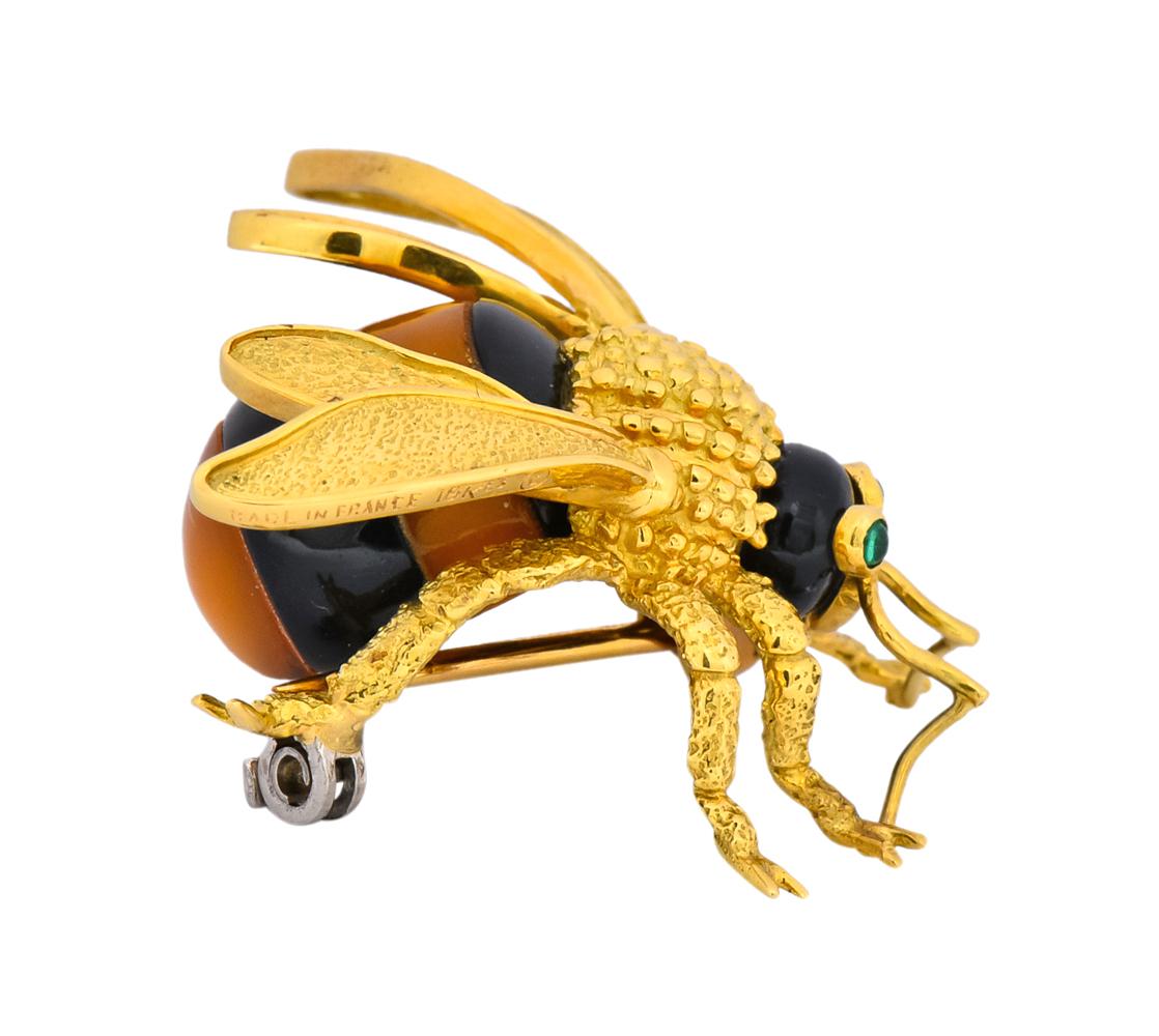 Brooch designed as textured gold bee with gold bead thorax and stippled wings

Onyx head is accented by two bezel set round cabochon chrysoprase eyes measuring 1.7 mm each

With oval cabochon abdomen comprised of bands of onyx and amber measuring