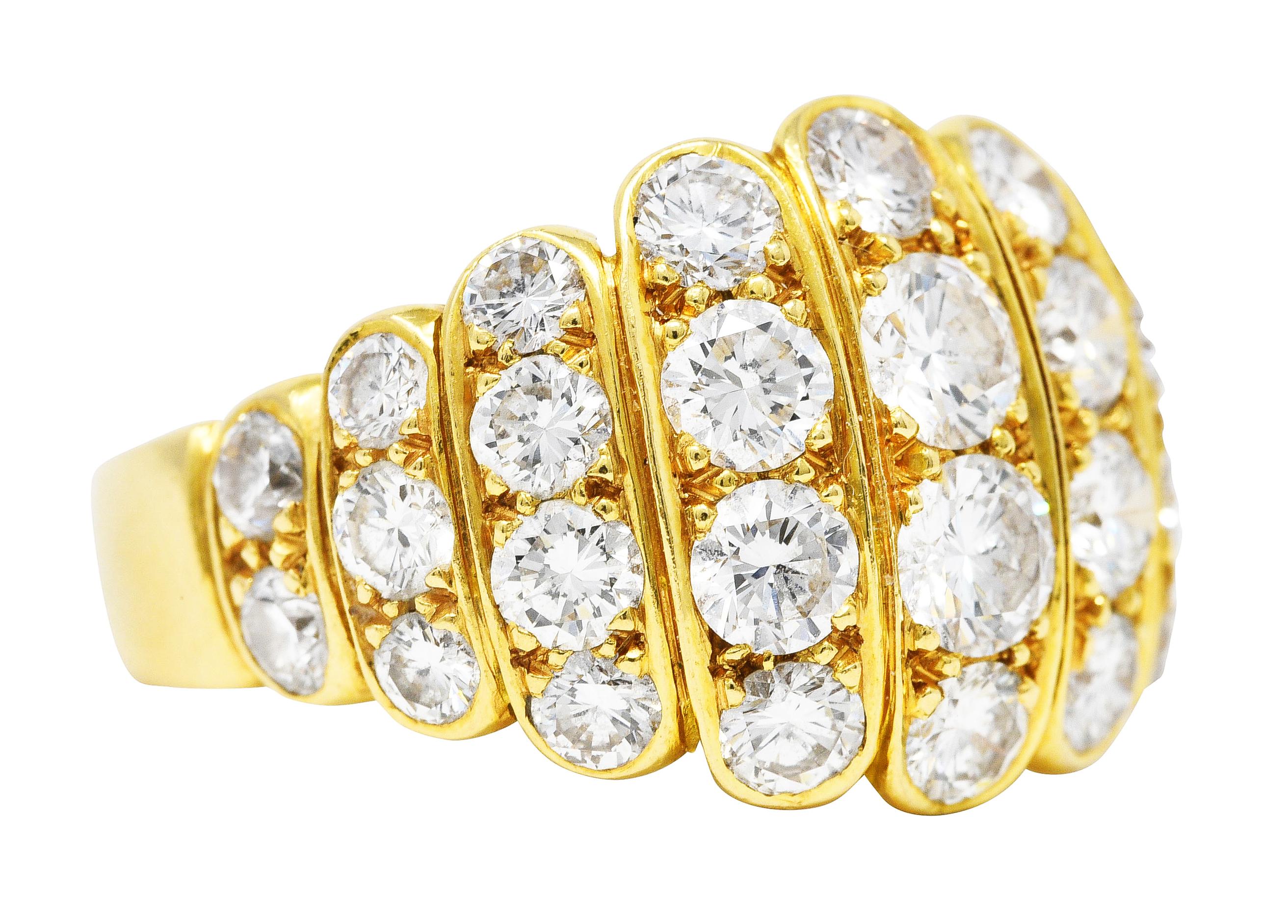 Der Bandring ist nach vorne durch abgestufte Stege geteilt. Besetzt mit runden Diamanten im Brillantschliff - in der Größe abgestuft. Mit einem Gesamtgewicht von etwa 2,95 Karat, Farbe F/G und Reinheit VS. Ergänzt durch eine stilisierte