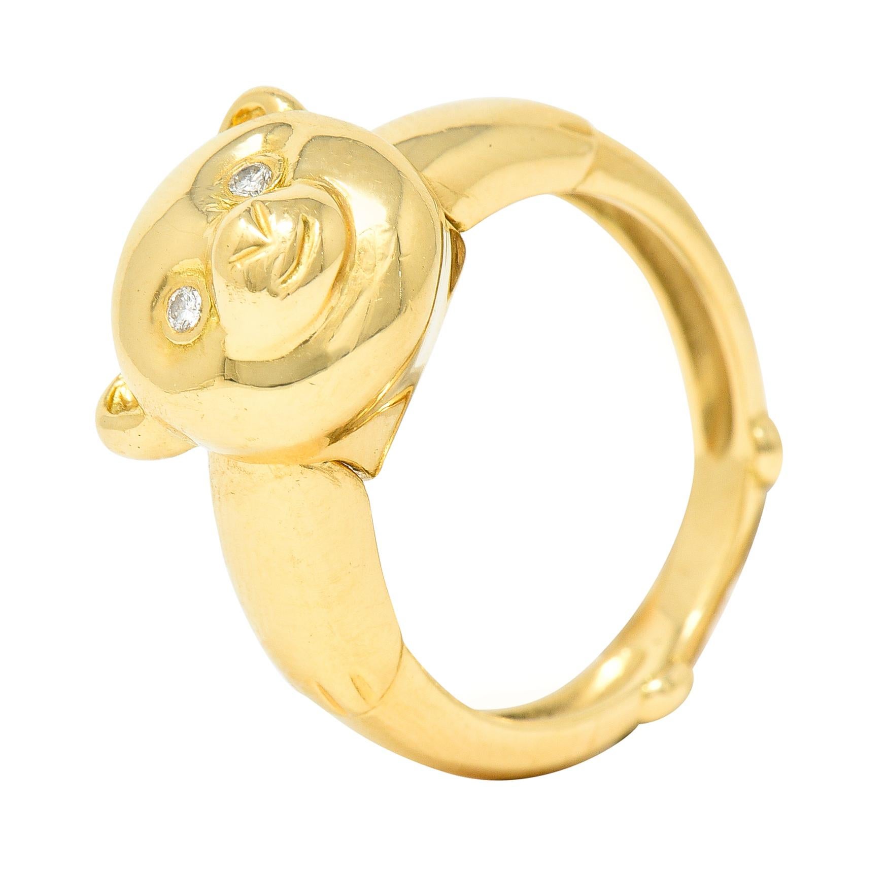 Gold band ring has paws subtly designed into shank. While head is dimensionally rendered and pivots forward to reveal concealed bale. Converting band ring into a stylized and circular teddy bear pendant. Eyes are two round brilliant cut diamonds