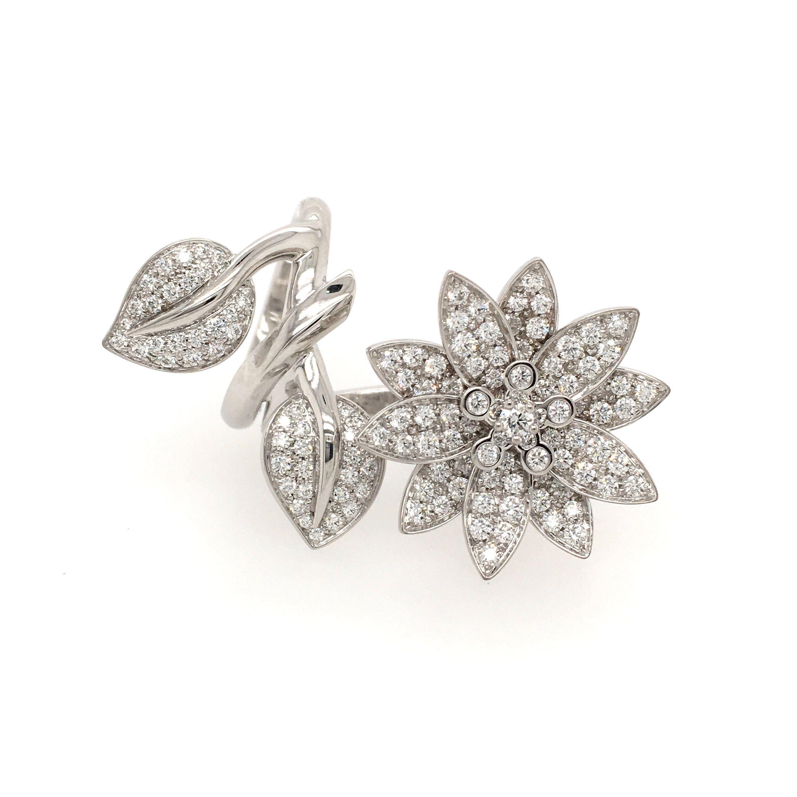 An 18 karat white gold and diamond Lotus Between The Finger ring. Van Cleef & Arpels. Designed as a pave set diamond flower blossom, accented by two pave set diamond leaves, to a sculpted 18k white gold vine forming the hinged double hoop. Total