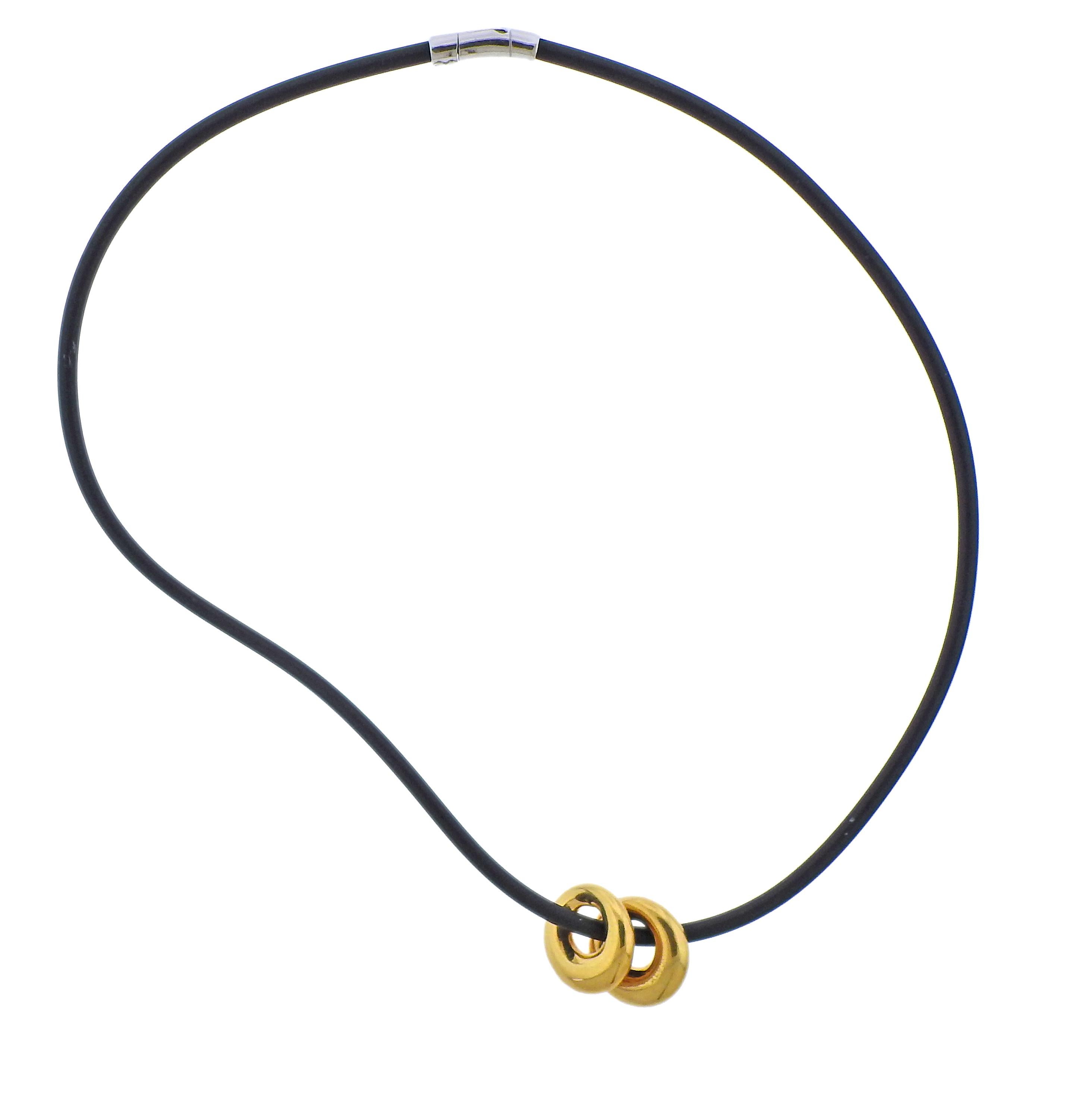 Two 18k yellow gold circle pendants by Van Cleef & Arpels, suspended on a black 18k gold Italian-made rubber cord necklace. Necklace is 18