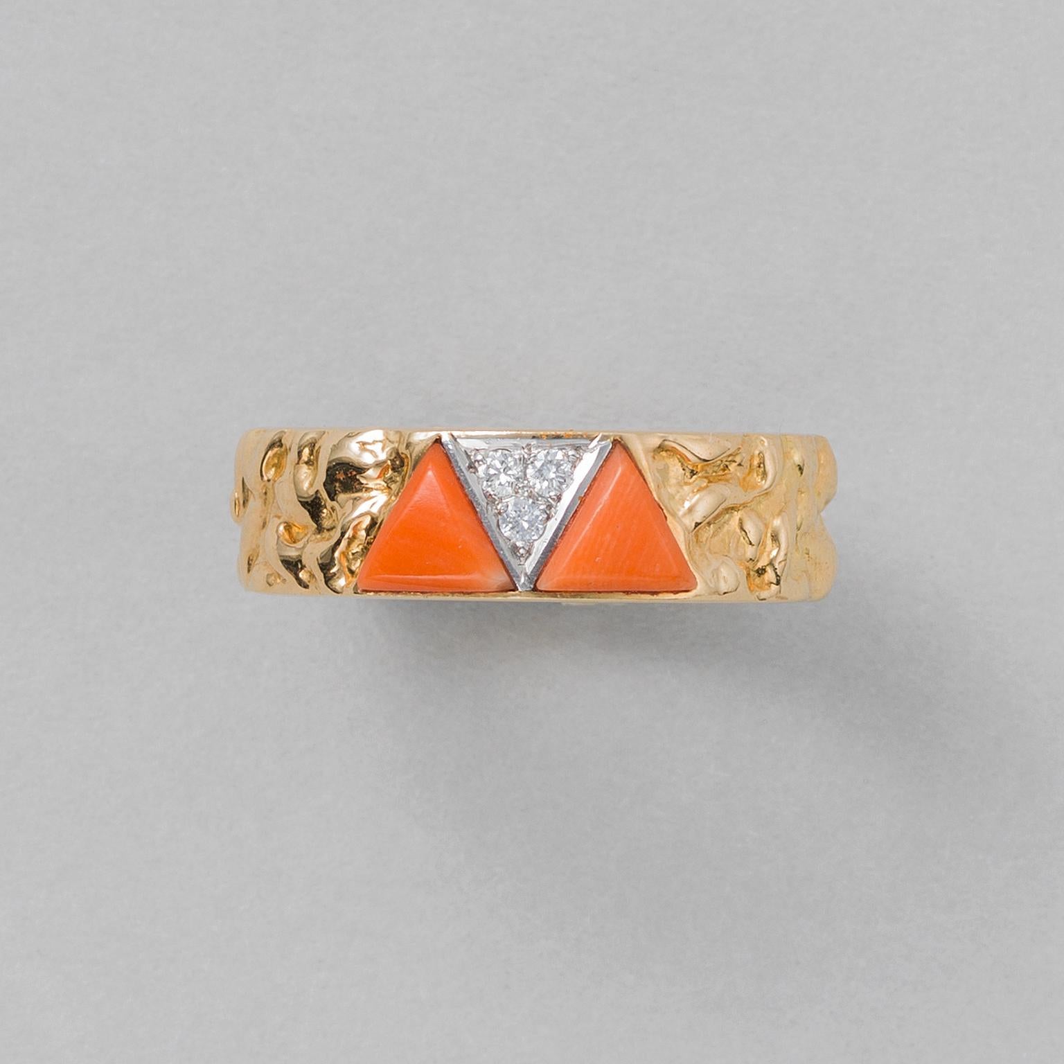 An 18 carat gold band ring with irregular texture set with two triangular pieces of coral with in between a juxta posed platinum triangle set with three brilliant cut diamonds, signed and numbered: VCA NEW YORK, 862 1, Made in France for Van Cleef &