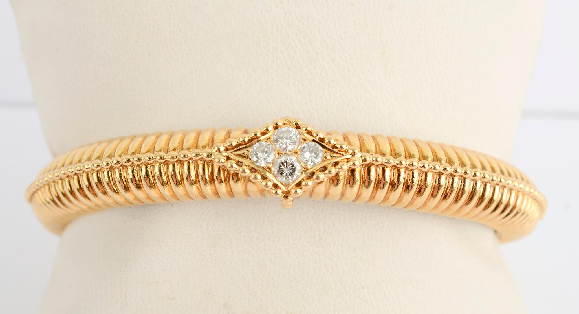 Bracelet bangle Van Cleef and Arpels, côtelé et articulé, avec quatre diamants au centre. Elles pèsent environ 0,8 carats. L'avant du bracelet a une largeur de 7/16 de pouce qui se réduit à 1/4 de pouce à l'arrière. Le diamètre intérieur est de 2