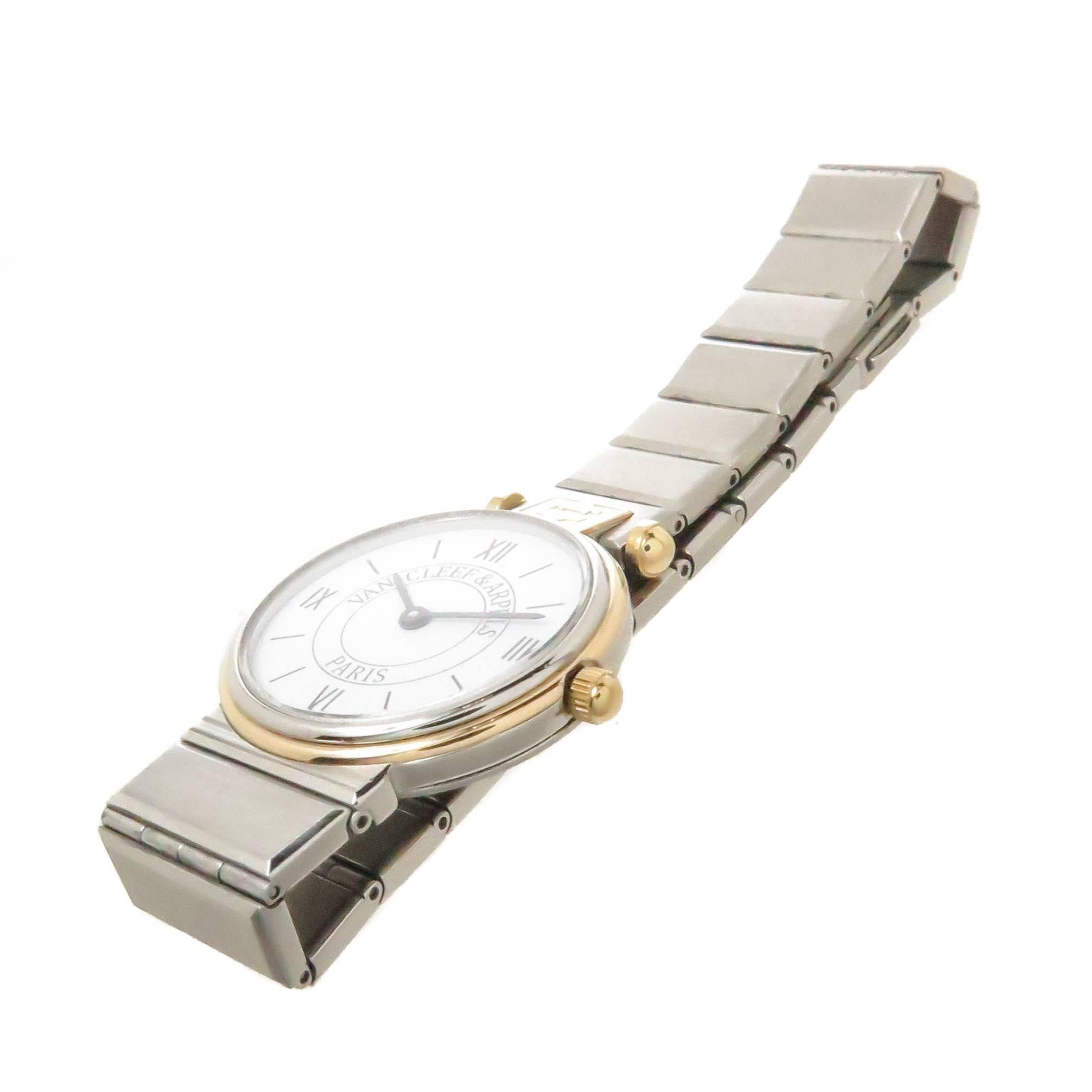Circa 1990s Van Cleef & Arpels Ladies La Collection Wrist Watch. 24 MM Stainless Steel case with Yellow Gold Bezel, Quartz Movement, white Dial with Black Markers. 1/2 inch wide Stainless Steel Bracelet. Total watch length 6 3/8 inches. Comes in a