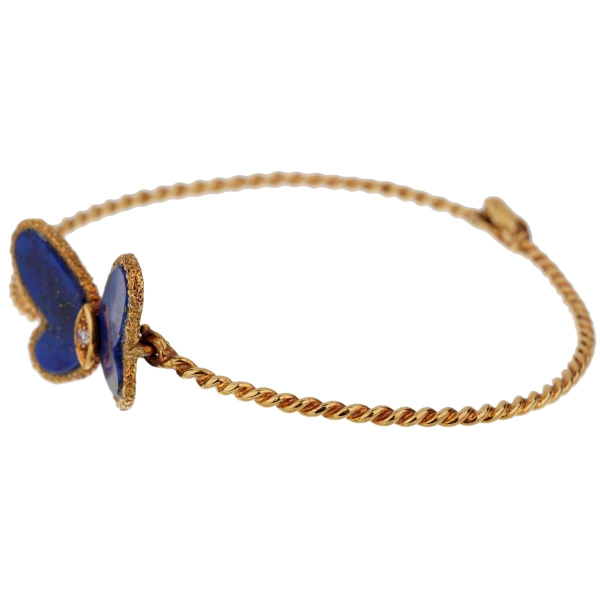 An iconic Van Cleef & Arpels butterfly bracelet showcasing a butterfly motif set with 2 lapis lazuli stones adorned by a .03ct round brilliant cut diamonds in 18k yellow gold. The bracelet measures internally 6 3/4