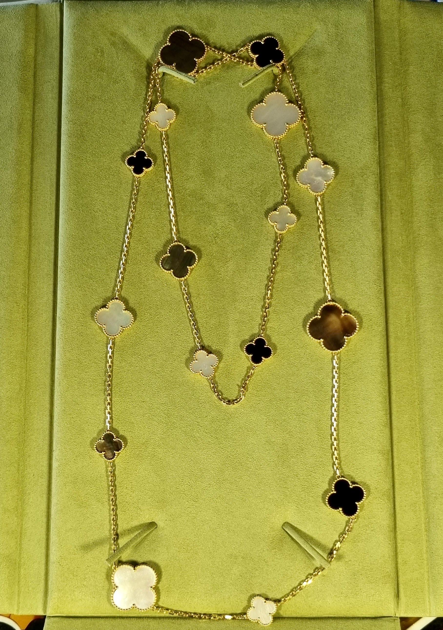 Superbe collier en or jaune 18 carats Van Cleef & Arpels de la collection Magic Alhambra. Le collier comprend 16 motifs iconiques de trèfle à 4 feuilles alternant en taille, sertis de nacre blanche, de nacre grise et d'onyx et complétés par un bord