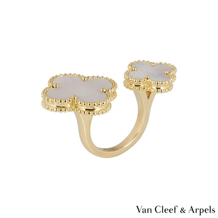 An 18k yellow gold Magic Alhambra Between the Finger ring by Van Cleef & Arpels. The ring features two clover motifs of different sizes, each set with a mother of pearl inlay and a beaded outer edge. The ring measures 4cm at the widest point, is a