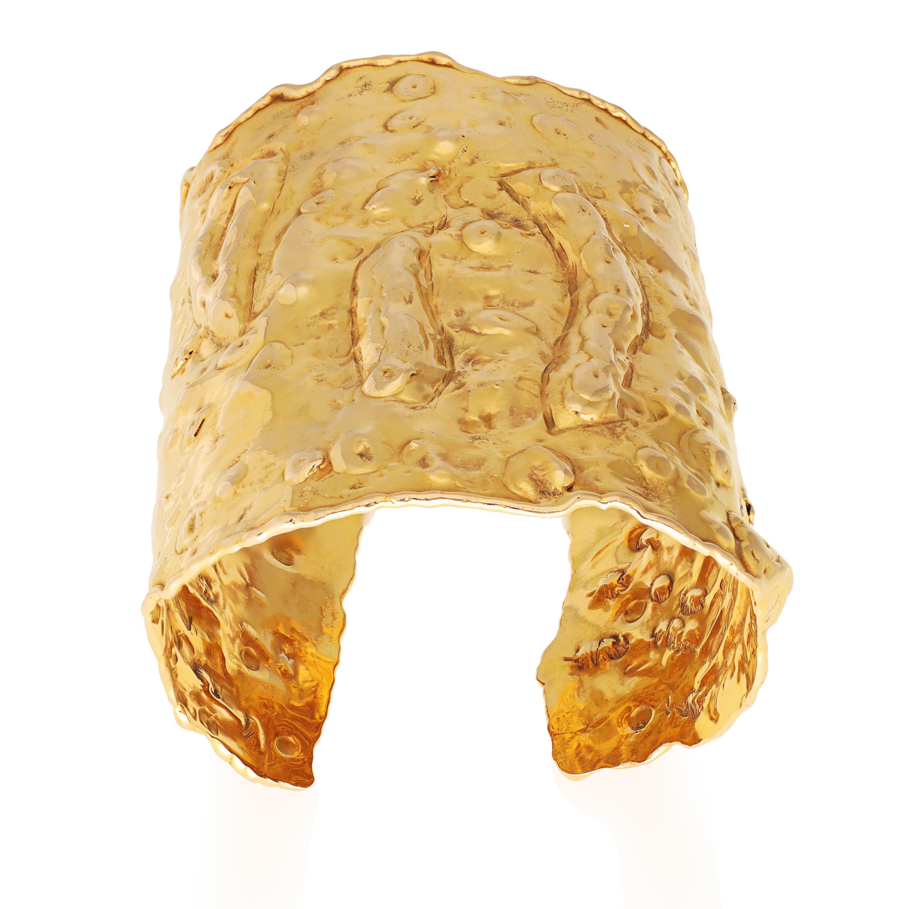 Ce bracelet manchette de grande envergure présente un design martelé de forme libre en or jaune poli et texturé. Sa surface est ornée de formes amorphes et dimensionnelles, et ses bords sont intentionnellement irréguliers. Ce bracelet est