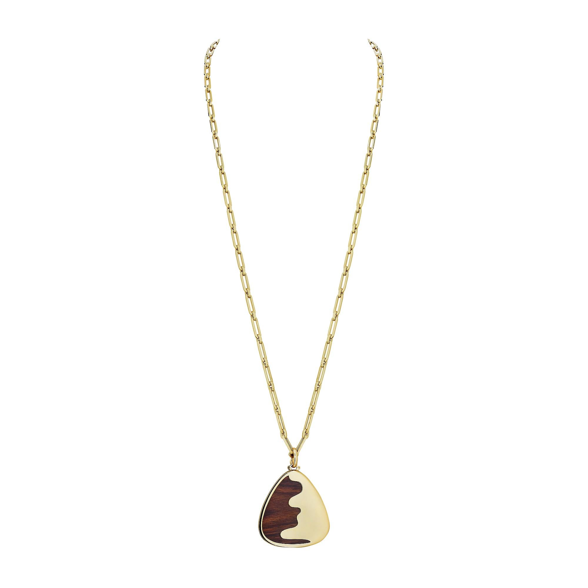 This Van Cleef & Arpels modernist abstract pendant is the perfect marriage of rosewood and polished yellow gold.  A triangular hand carved piece of rosewood is organically overlapped and framed with polished 18 karat gold, resulting in an incredible