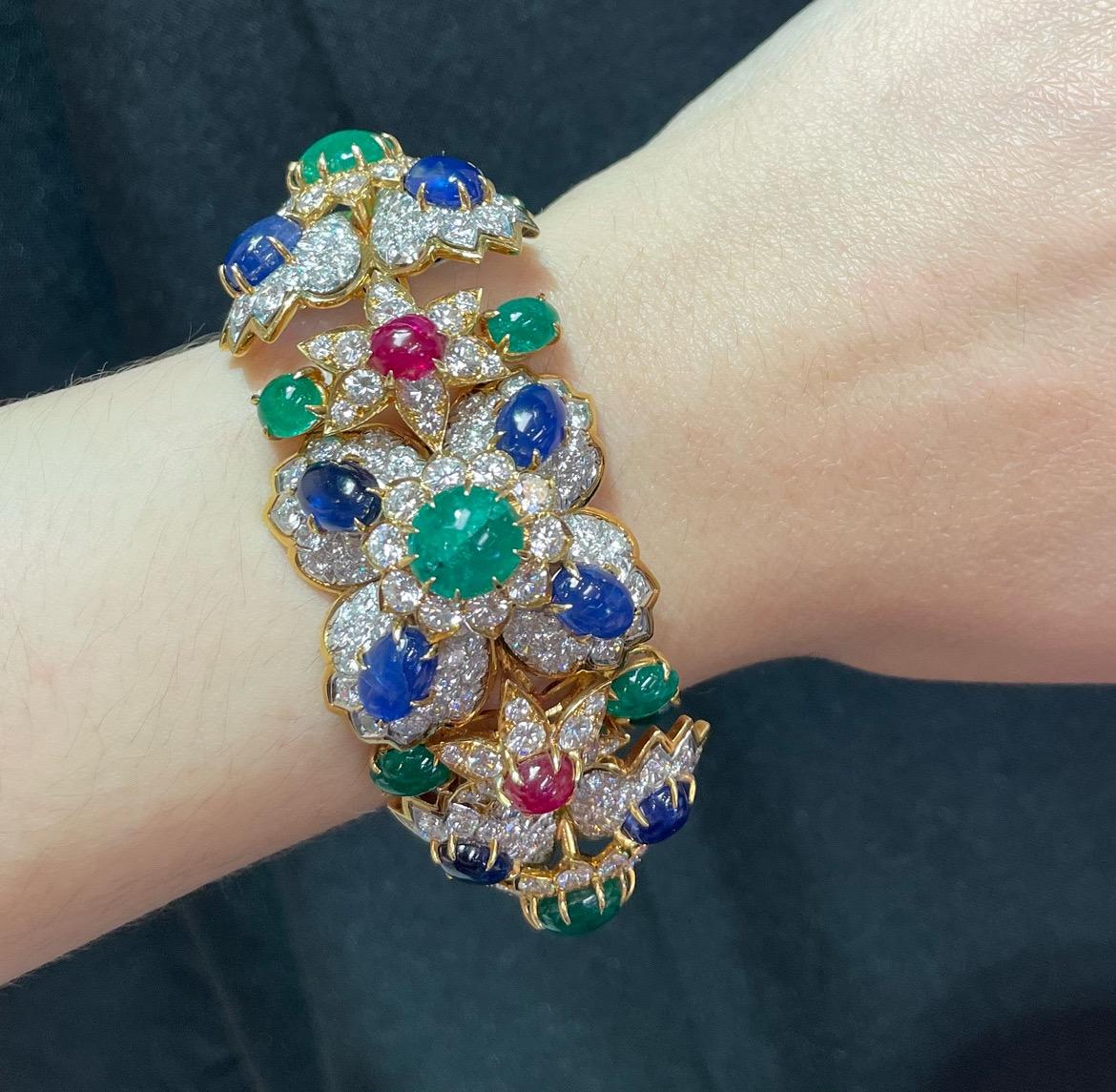 Van Cleef & Arpels Multi Gem Bracelet 

A beautiful multi-gem bracelet featuring a floral motif adorned with round and oval-shaped cabochon sapphires, emeralds and rubies, and round-cut diamonds.
The center of the bracelet converts into a