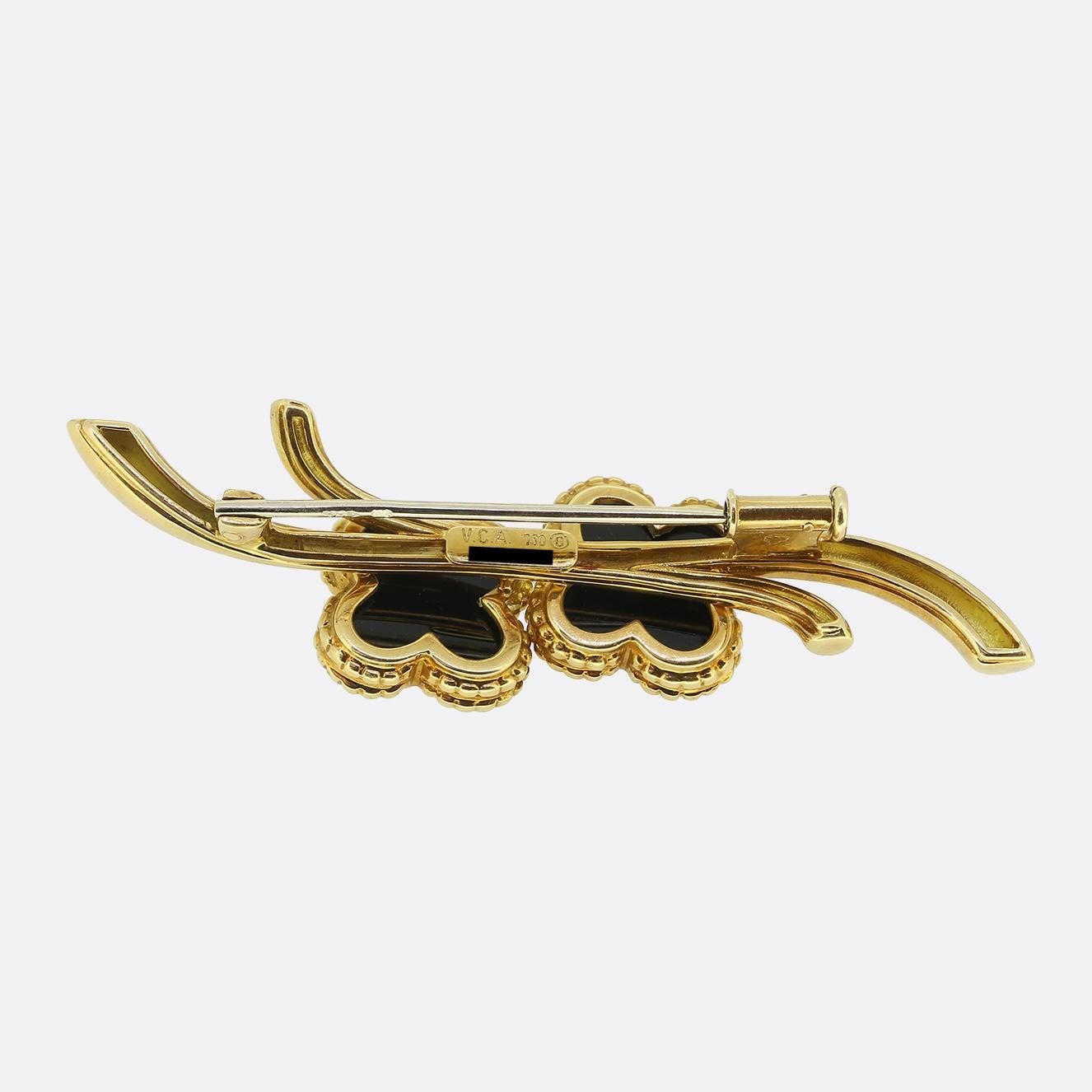 Here we have a chic and stylish brooch from the world renowned luxury jewellery house of Van Cleef & Arpels. Crafted from 18ct yellow gold, it features a sleek, flowing design with two iconic black onyx Alhambra motifs mounted in individual beaded
