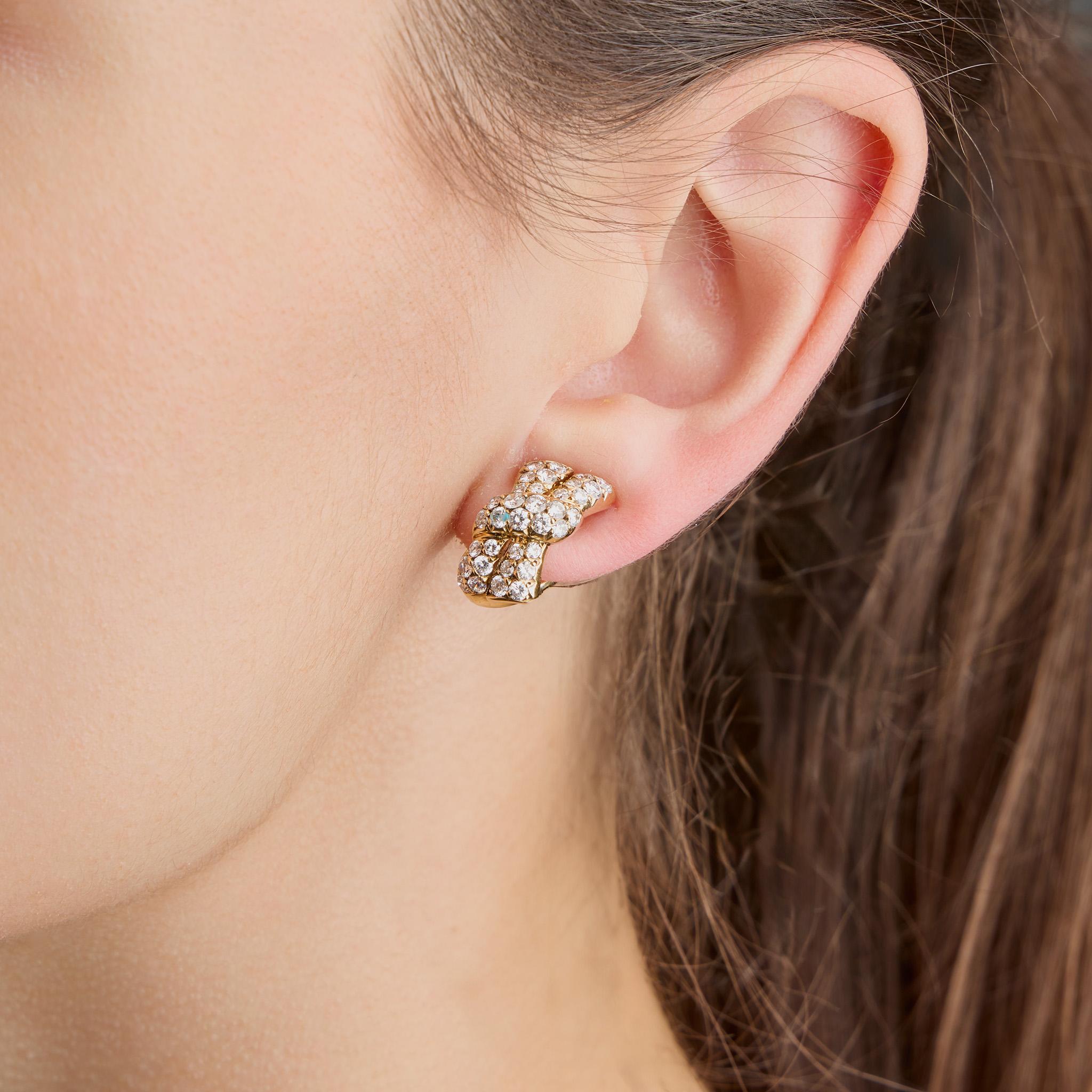 Diese aus den 1990er Jahren stammenden Ohrringe von Van Cleef & Arpels bestehen aus Diamanten und 18-karätigem Gold. Jeder Ohrring mit Omega-Klippverschluss ist als stilisierter Bogenknoten gestaltet und mit runden Brillanten besetzt. Diese