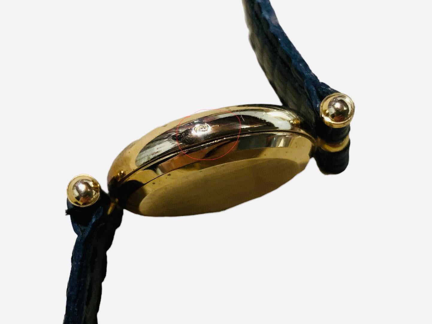 Il s'agit d'une montre-bracelet Van Cleef & Arpels Pierre Arpels pour femme. Elle présente un boîtier rond en or 18 carats/750, un cadran doré avec des chiffres romains et des aiguilles des heures et des minutes de couleur noire. Une vitre recouvre