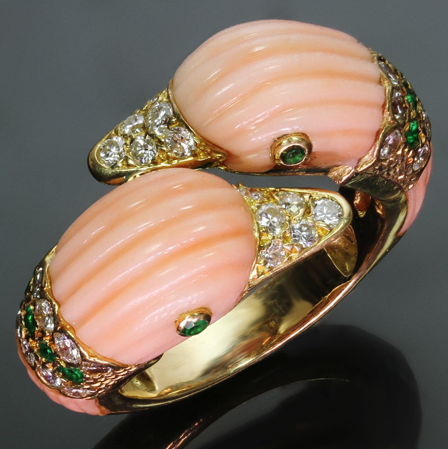This fantastic vintage Van Cleef & Arpels bypass ring is crafted in 18k yellow gold and features a pair of carved fluted pink coral dolphins accented round-cut green emerald and 32 brilliant-cut round F-G-H VS1-VS2 diamonds. Made in France circa