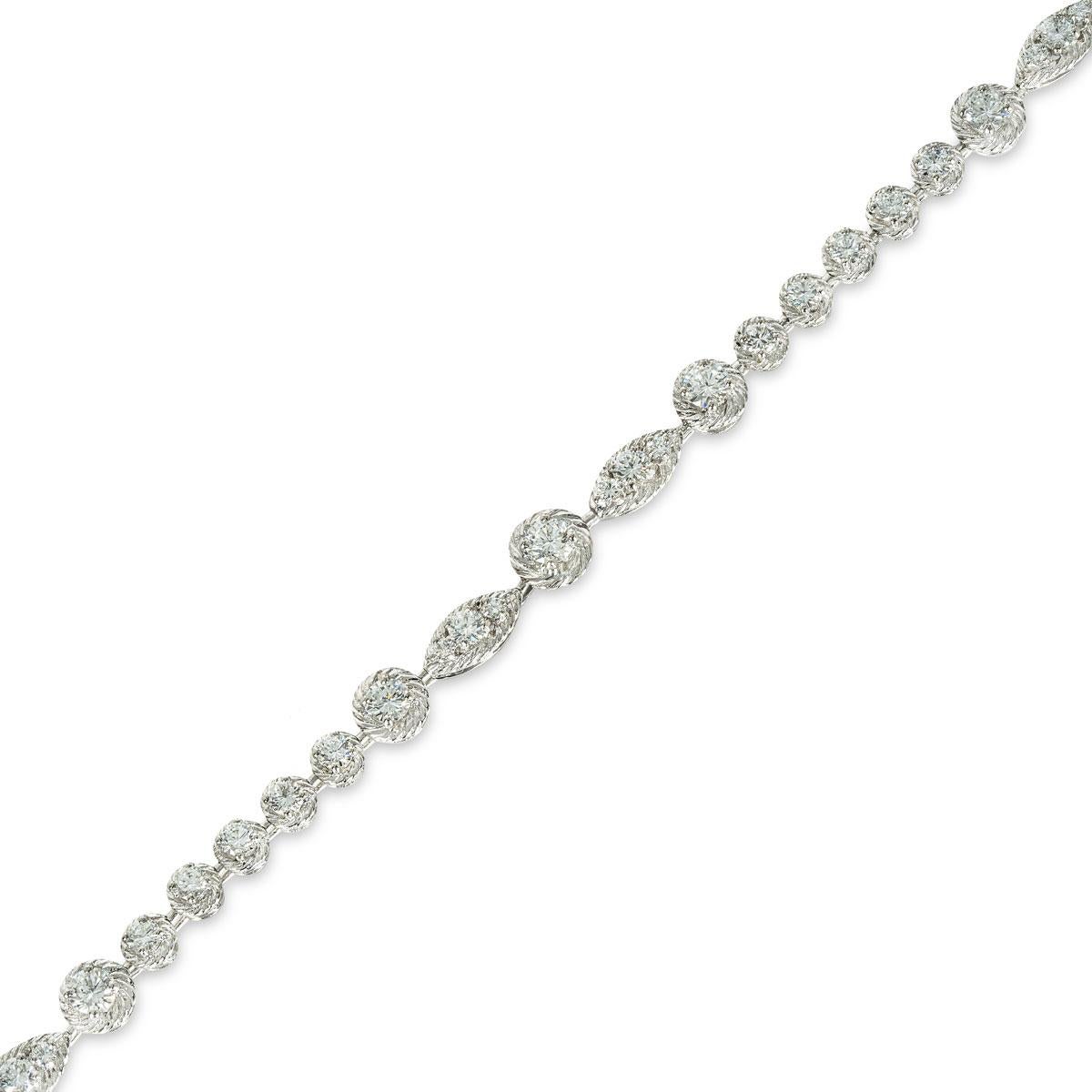 An elegant platinum diamond necklace by Van Cleef & Arpels. The necklace features stations alternating between 1 and 3 round brilliant cut diamonds with a decorative surround. A total of 84 round brilliant cut diamonds are set throughout the