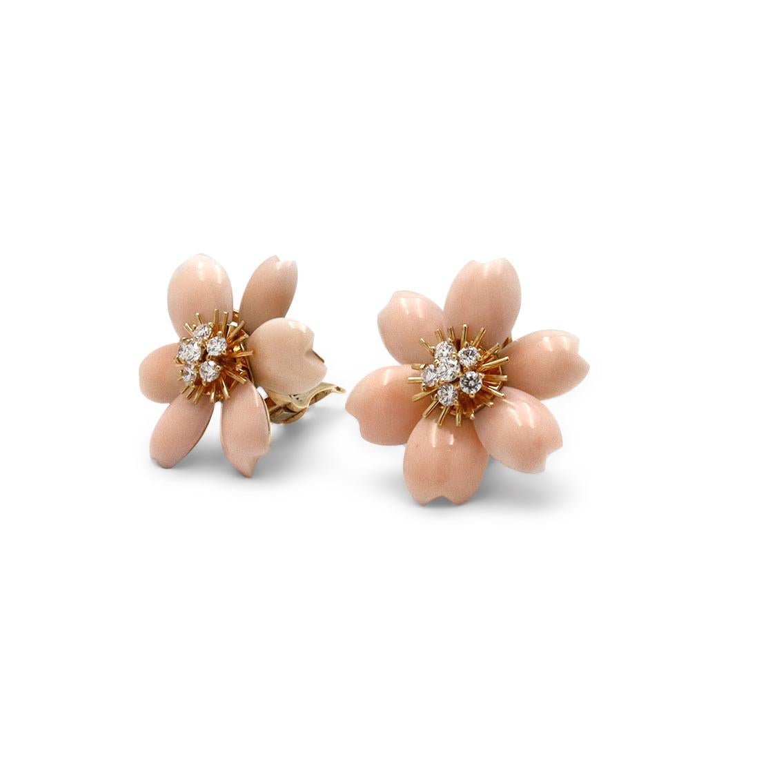 An authentic pair of Van Cleef & Arpels 'Rose de Noël' earclips crafted in 18 karat yellow gold featuring delicately carved pink coral petals. Each earring is set with 6 glittering round brilliant diamonds weighing an estimated 0.98 carats for the